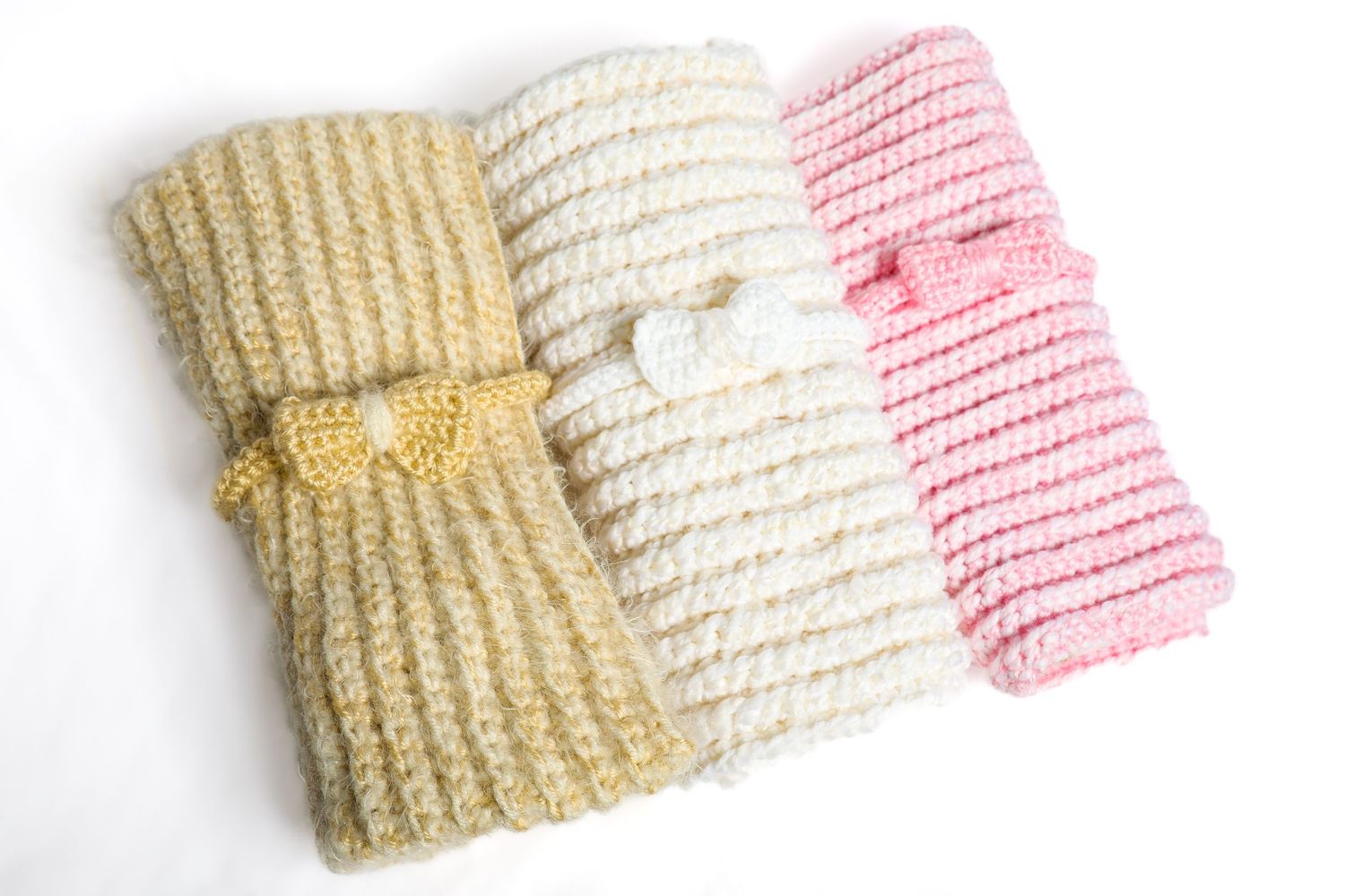 Knitted baby hats in pink, cream, and beige colors arranged in a row.