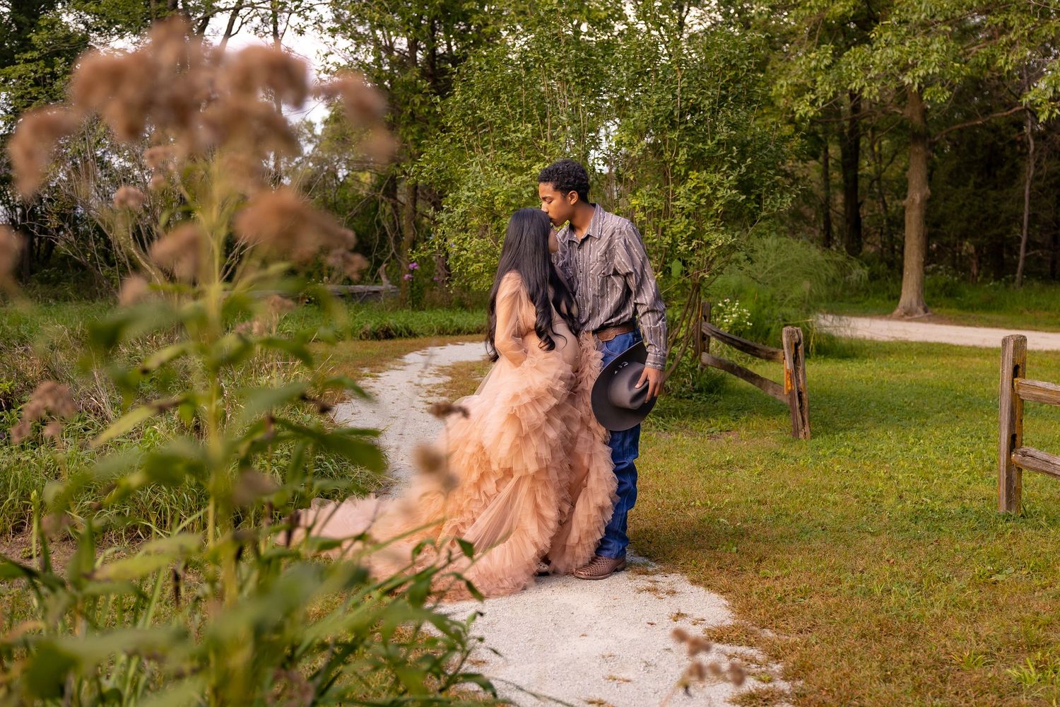 A professional groomer uses tools to carefully trim and groom a large fluffy dog outdoors in a park setting.