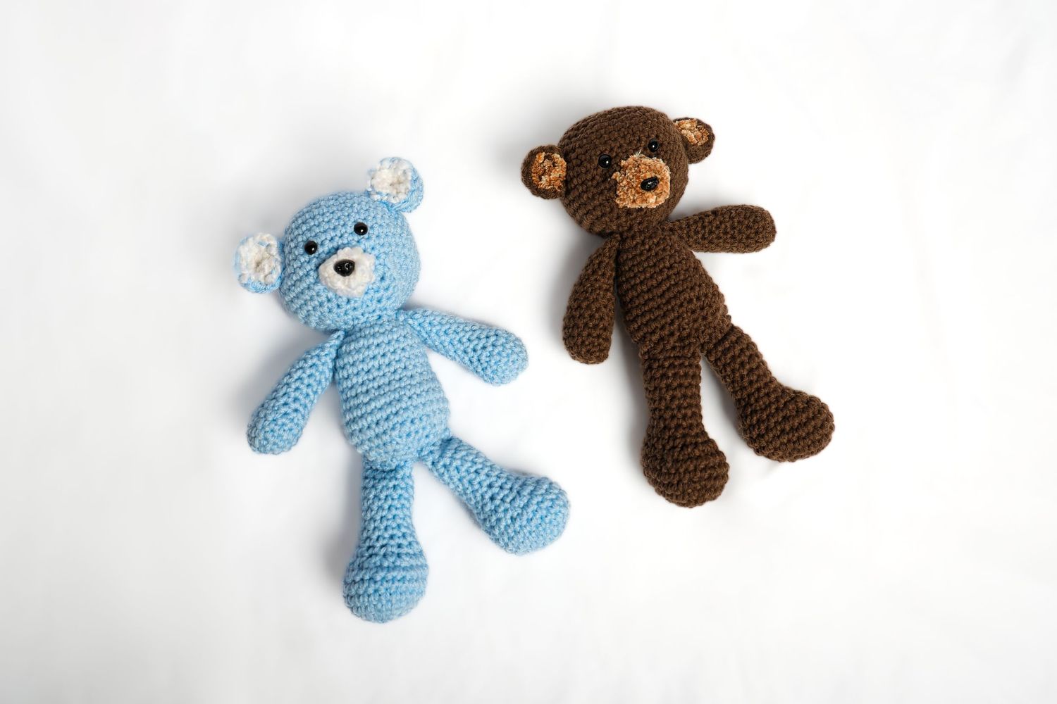 Blue and brown handmade crochet teddy bears positioned side by side.