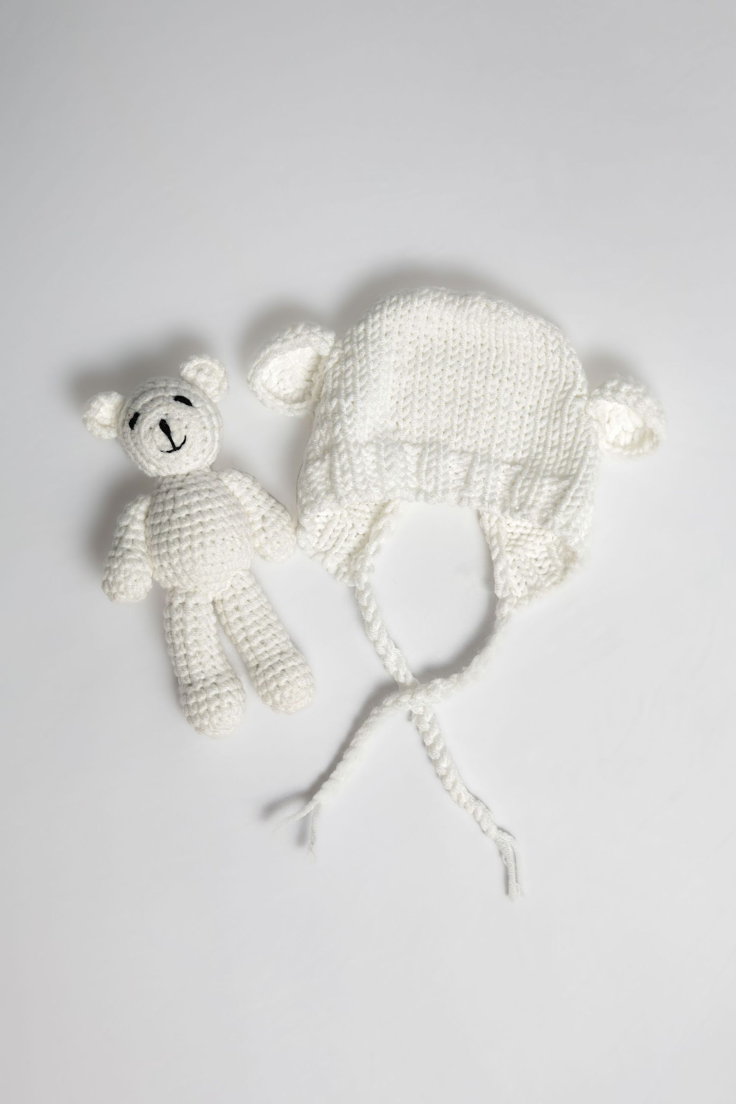 White knitted baby bonnet or hat shown in different angles on gray background.