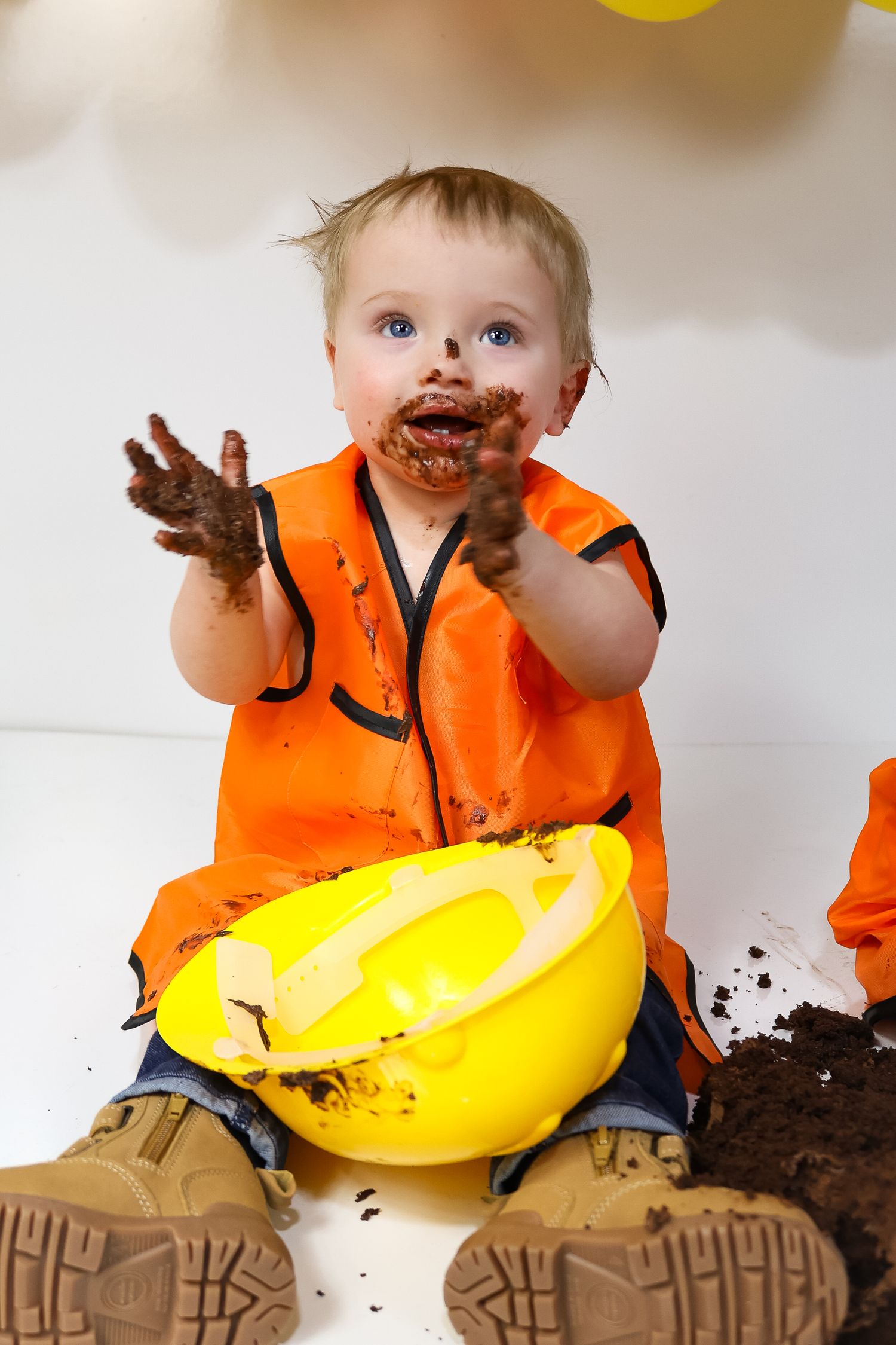 Construction themed setup with chocolate cake and work boots against balloon backdrop.