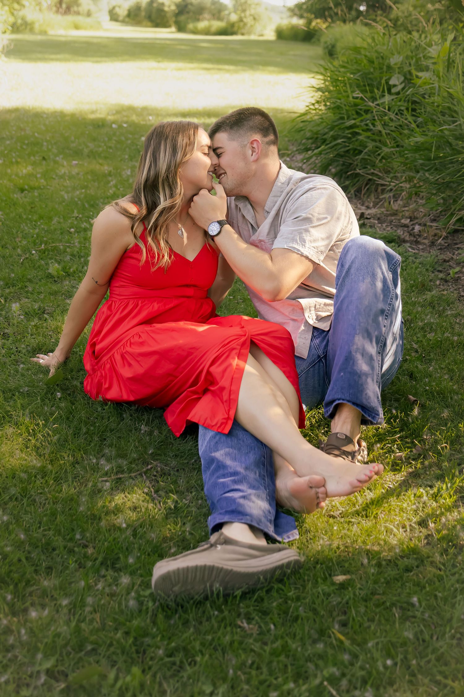 Romantic couple sharing intimate moment while lying in green summer grass.