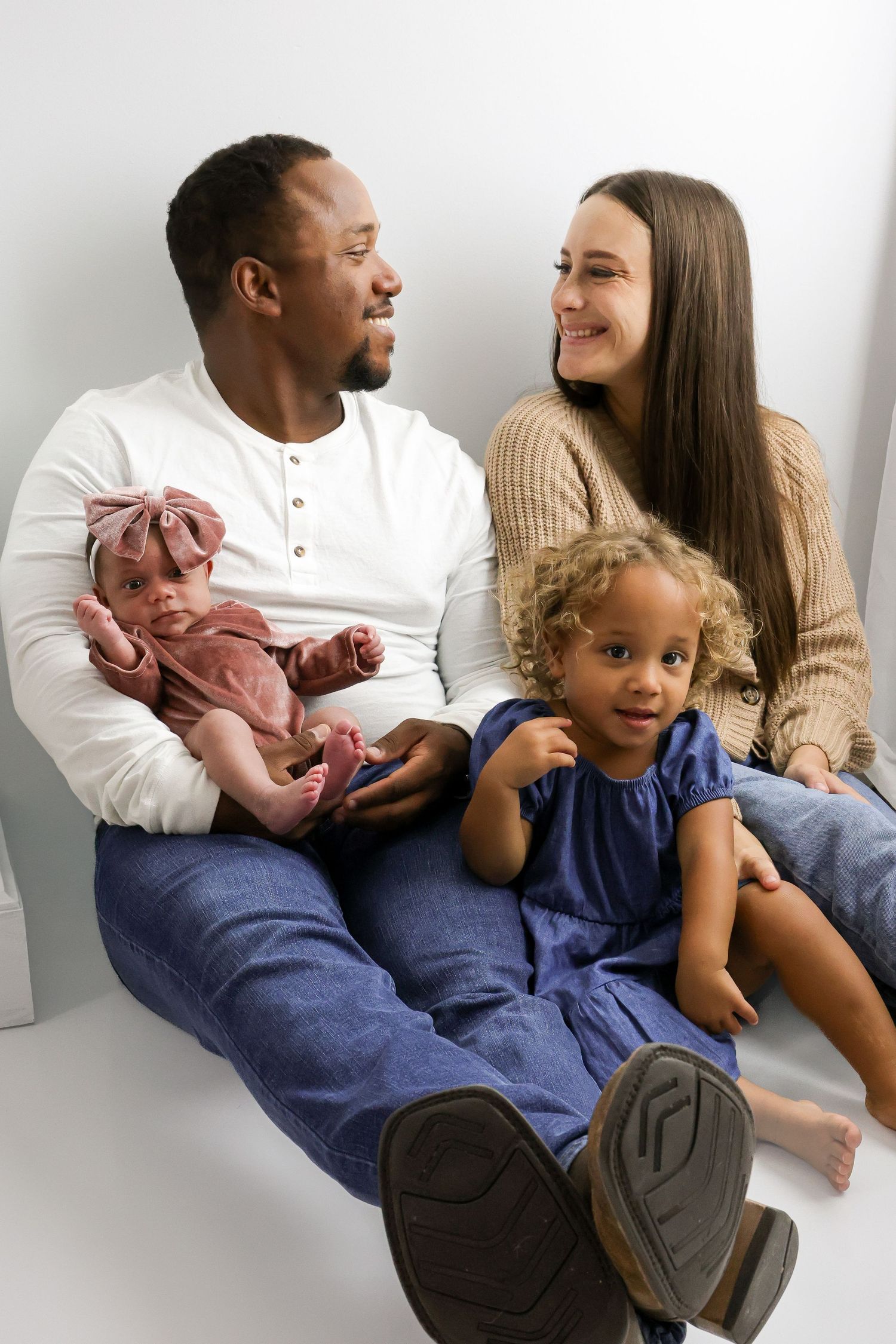 A loving family sits together on a couch in a series of candid moments showing their closeness and affection.