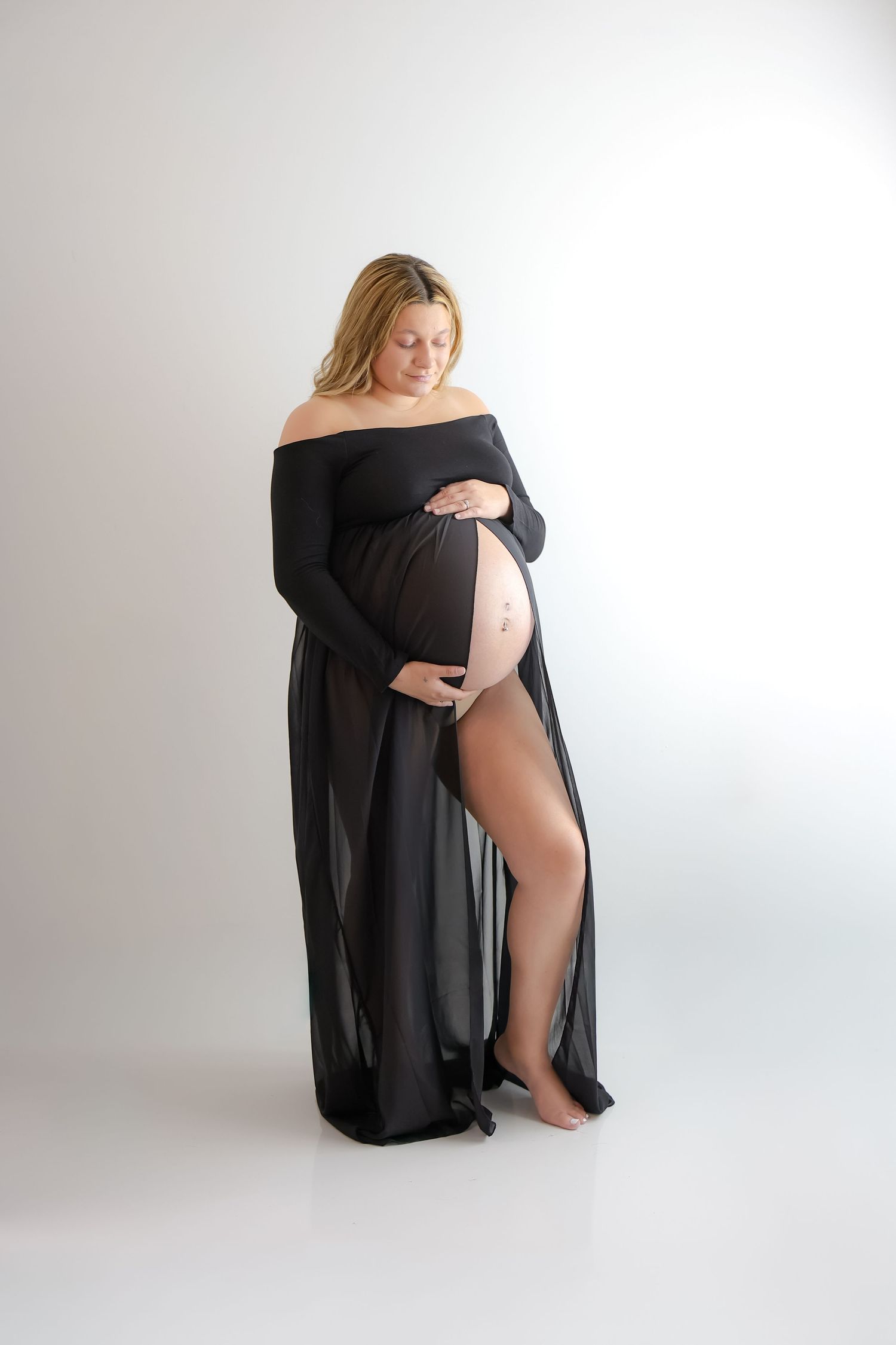 Artistic maternity photo series showing silhouette in flowing black fabric against white background.
