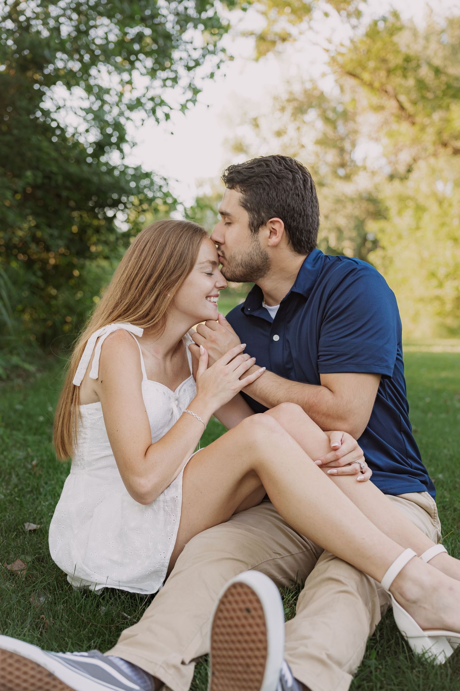 Intimate couple sharing tender moments together on grassy lawn.