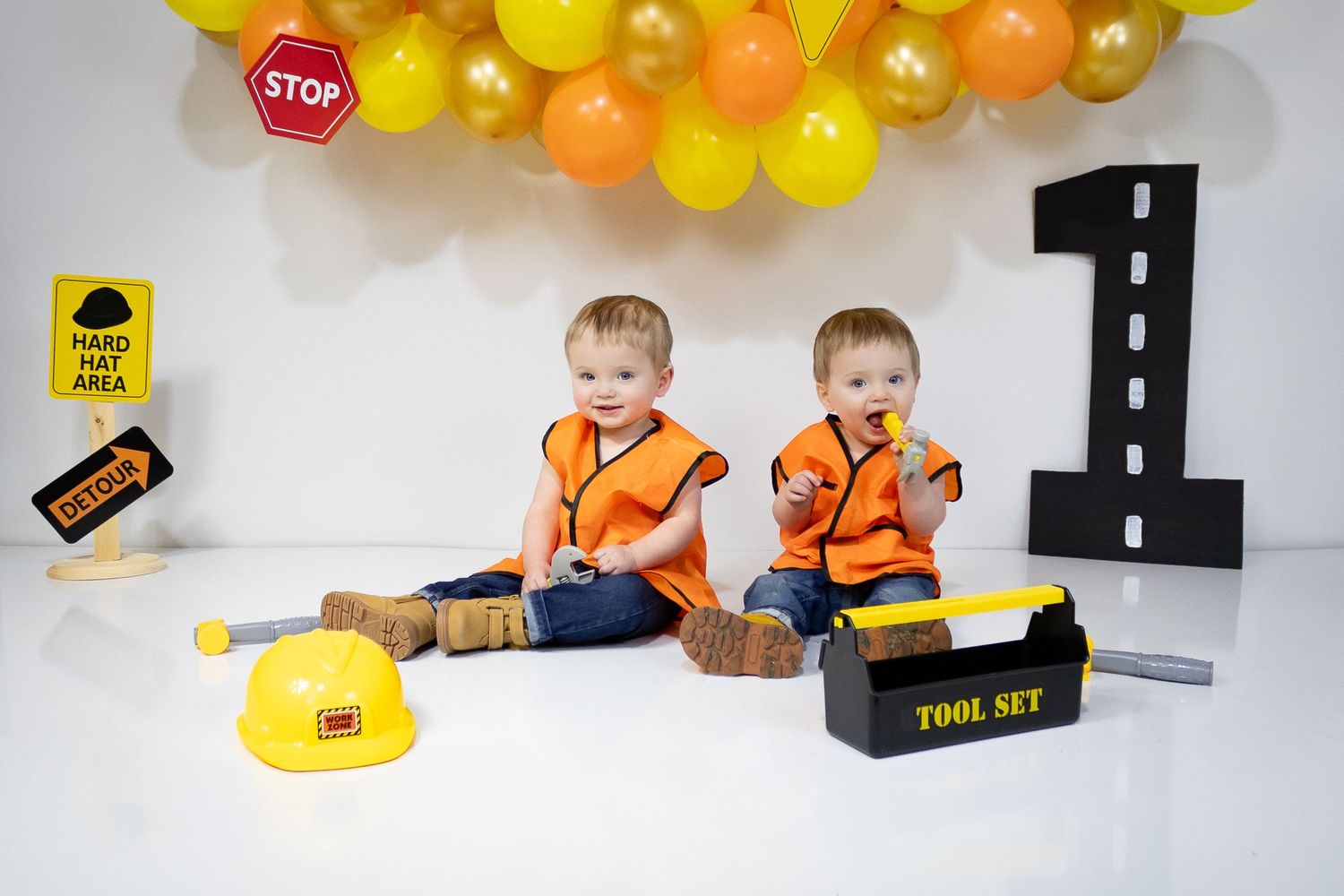 Children play with colorful wooden toy cars and road signs on a white surface.