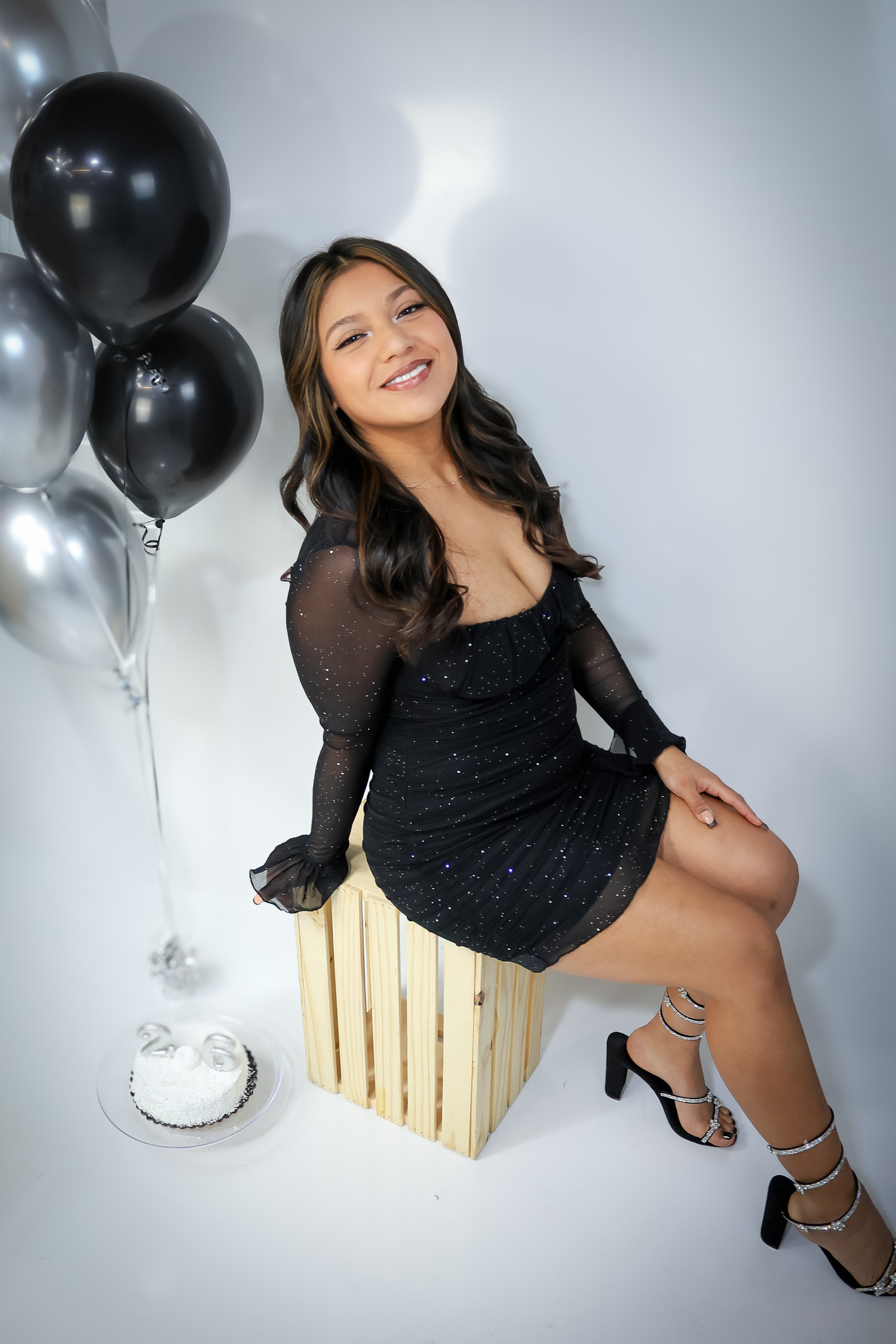 Studio portrait session with black and silver balloons against white background.