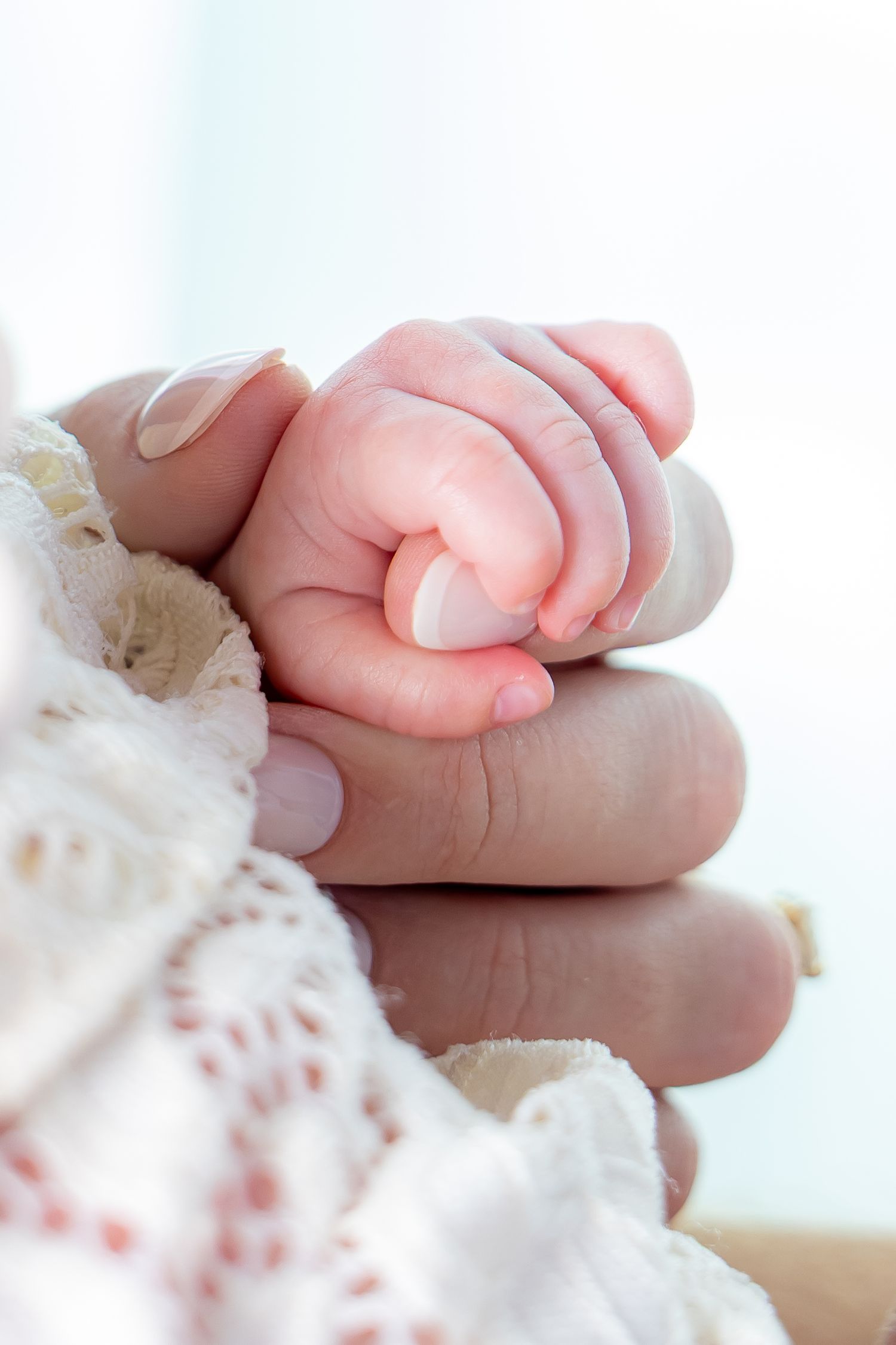 Soft focus image of small baby feet against white lace fabric.