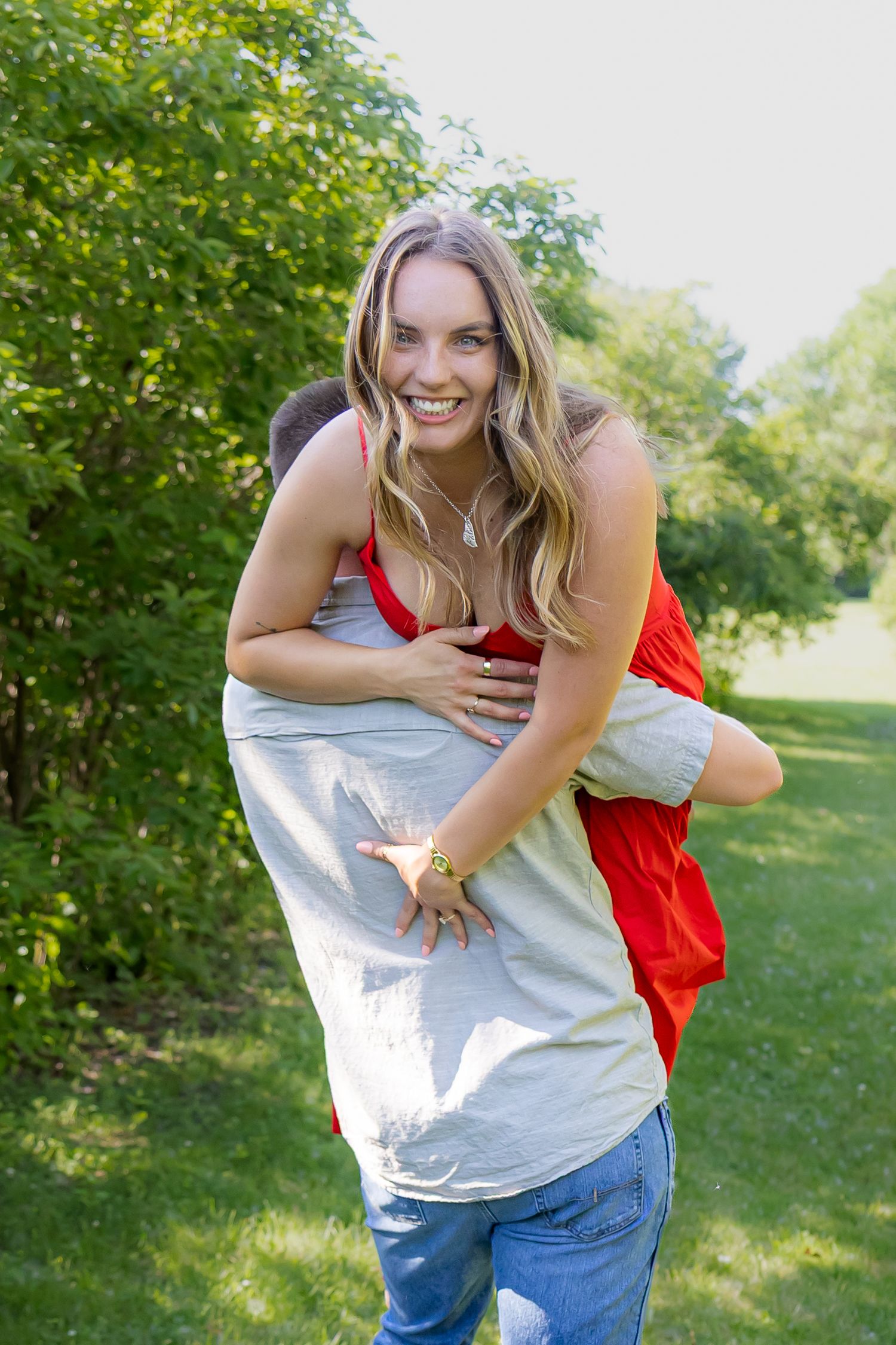Playful couple in casual clothes having fun outdoors in sunny park setting.