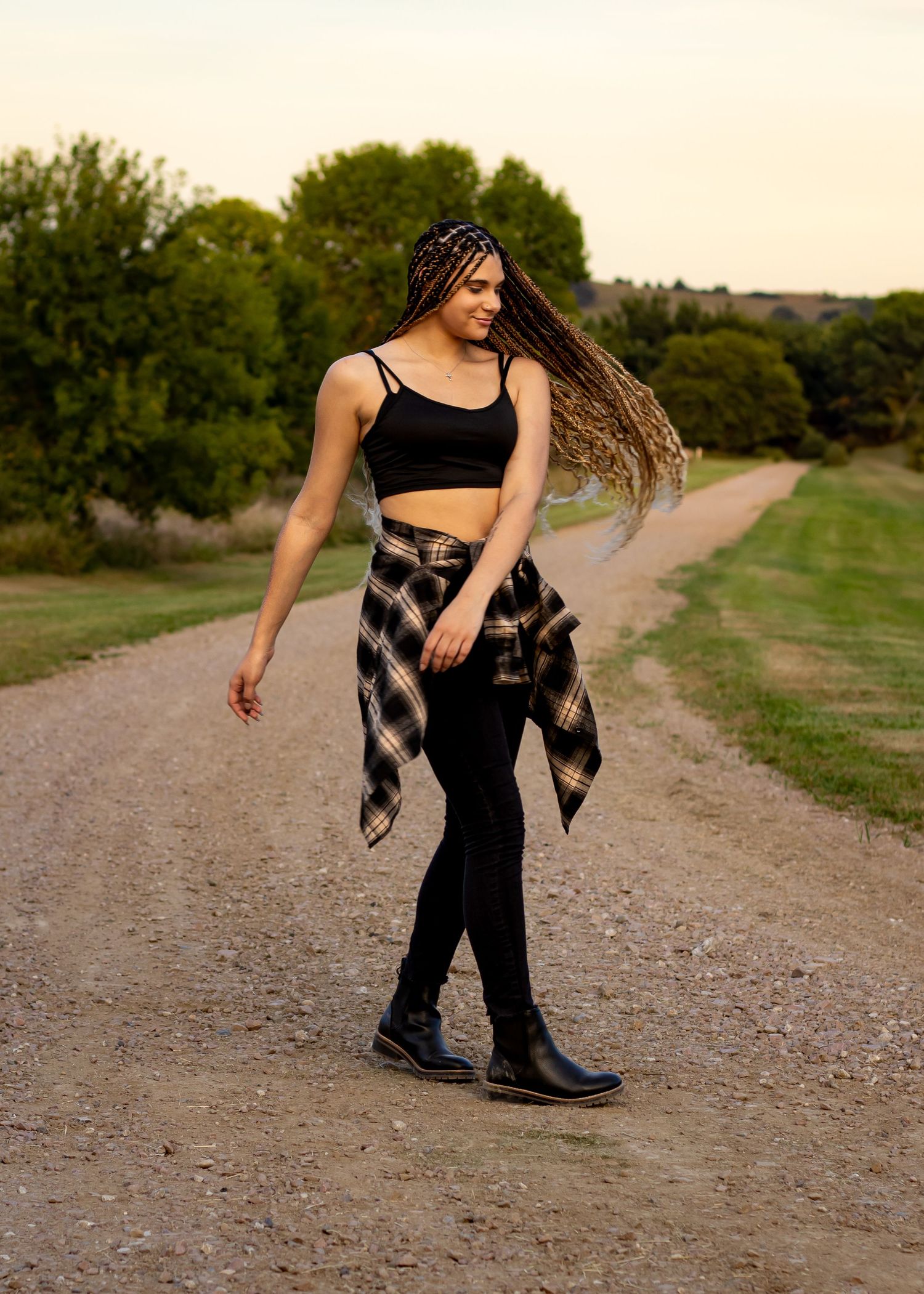 A person in black attire walks along a country path during golden hour.