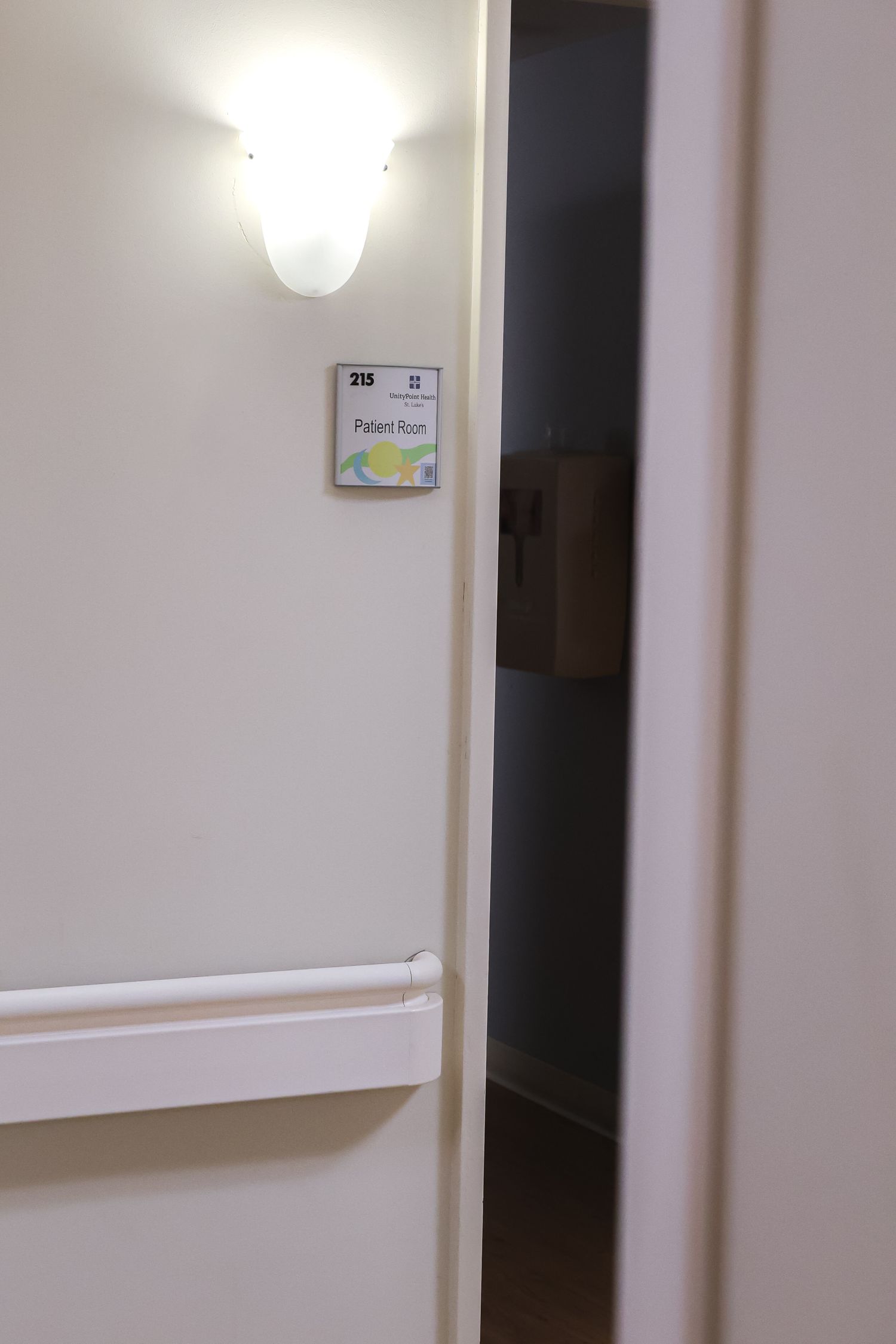 Hospital hallway with white walls and mounted handrails.