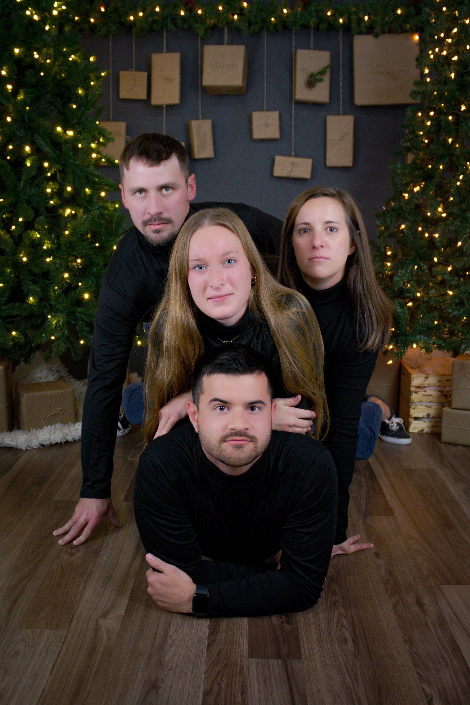 Group photo session with Christmas tree and decorative wall art in background.