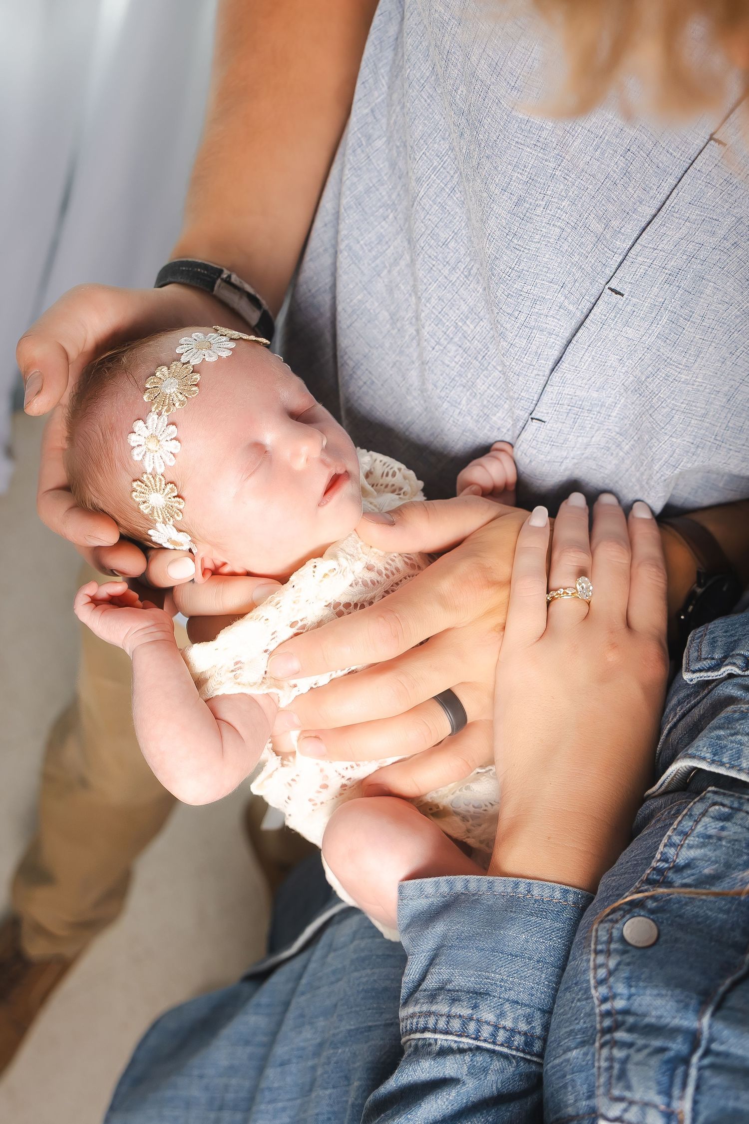 Close-up of tiny hands being held with delicate lace details.