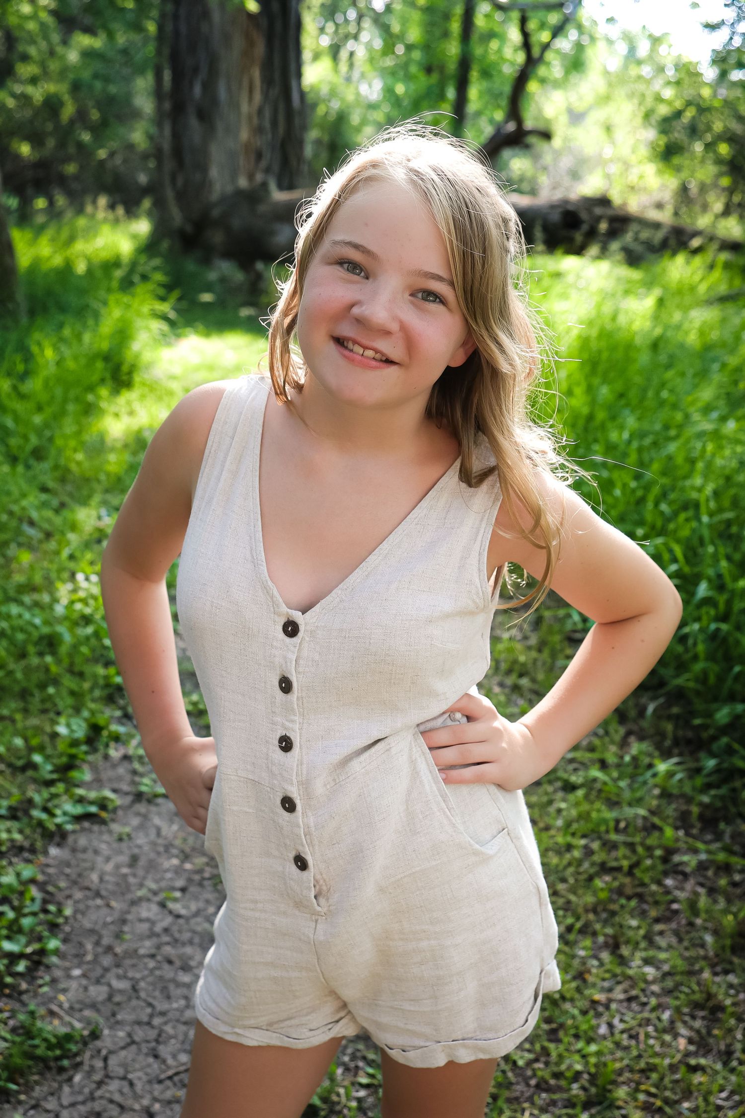 Person in cream colored romper strikes fun poses outdoors in natural lighting.