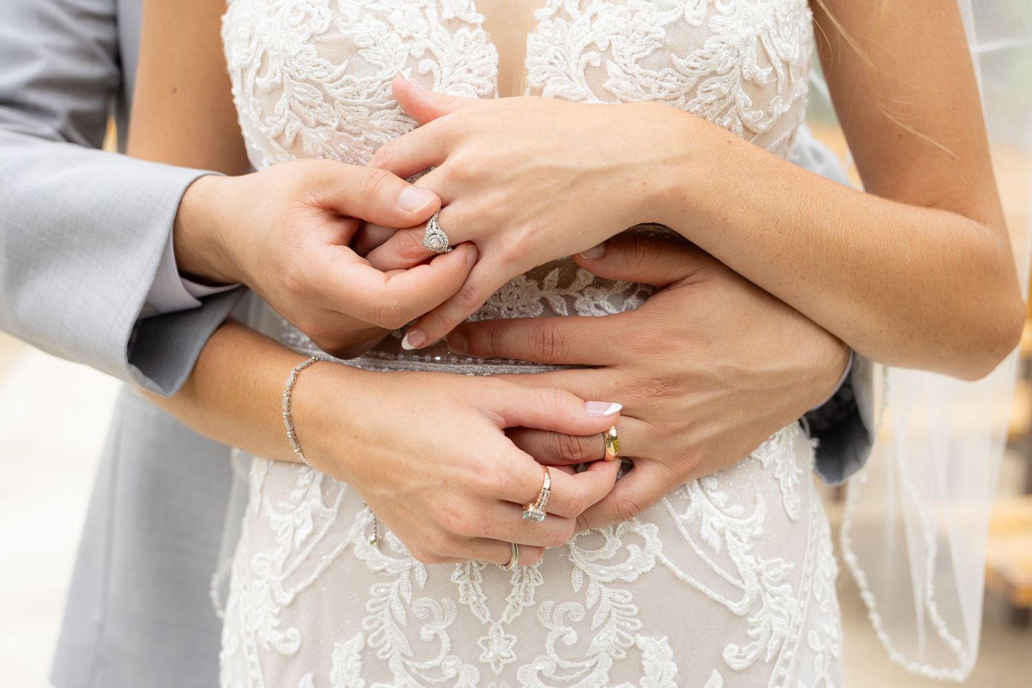 Close-up shots of hands wearing a delicate white lace wedding dress with intricate beaded details.