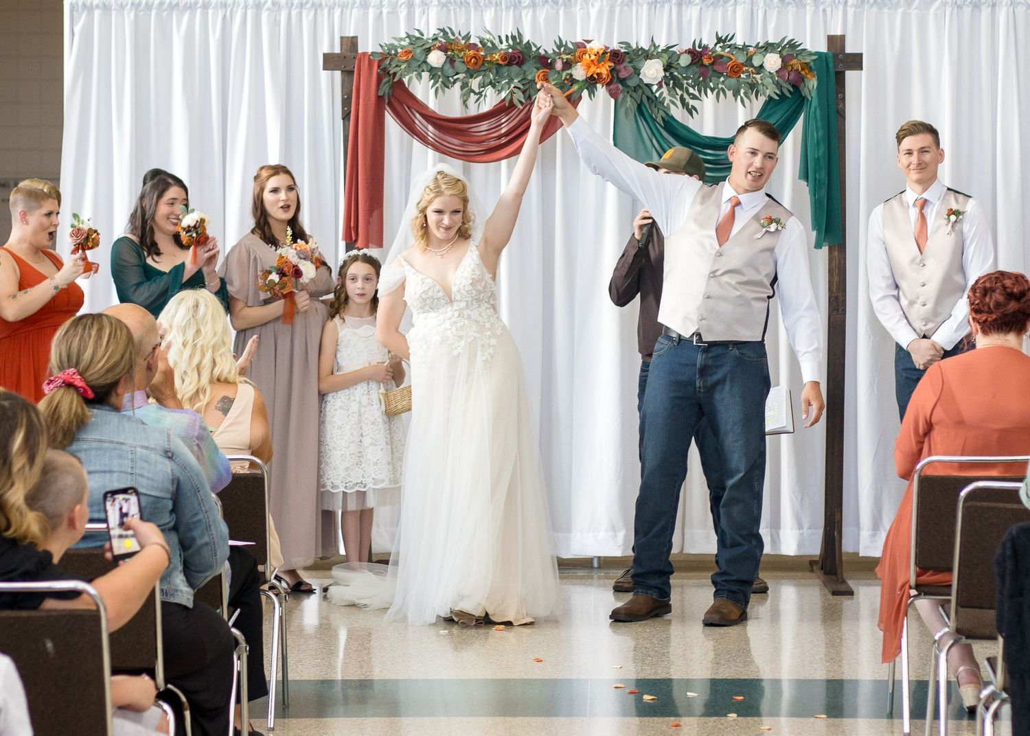 Panoramic view of a wedding ceremony setup with white drapes and autumn-colored floral decorations.