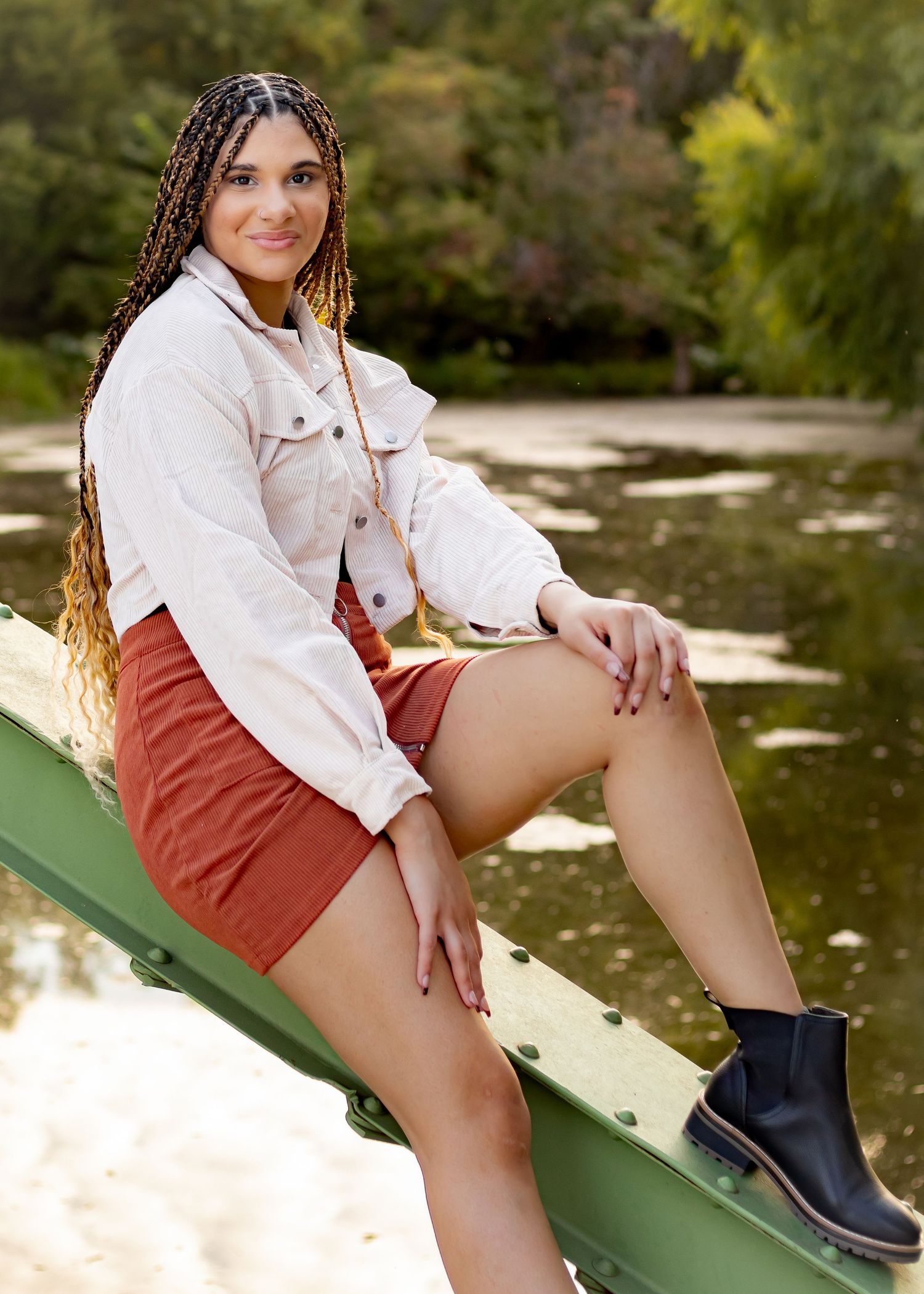 Outdoor fashion shoot on green bridge wearing white jacket and black boots.