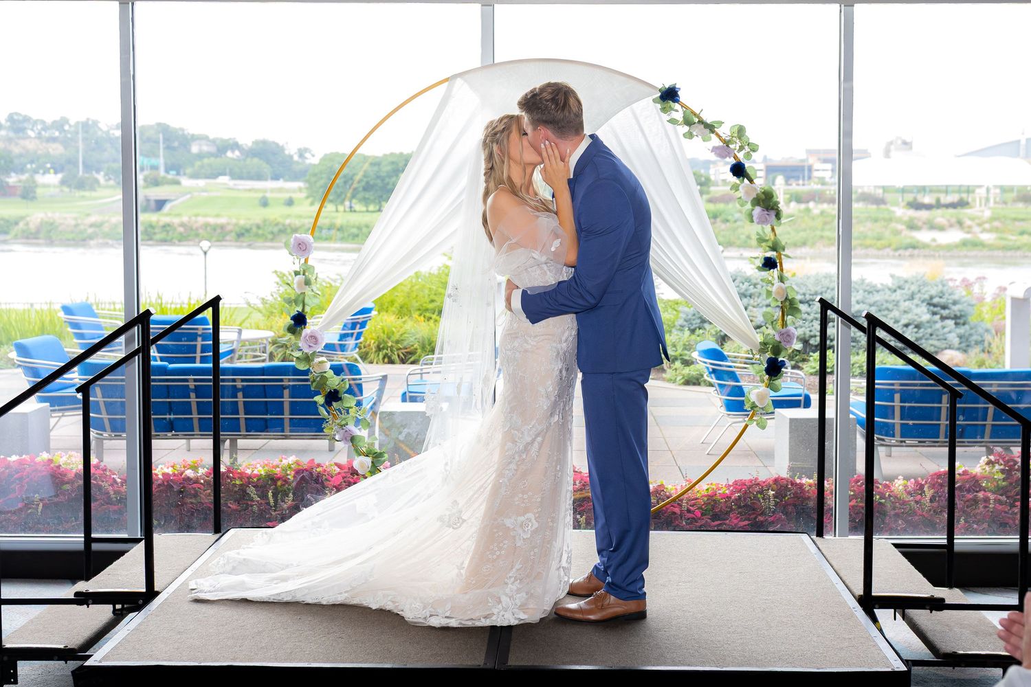 Wedding couple sharing intimate moments under an outdoor pavilion overlooking water.