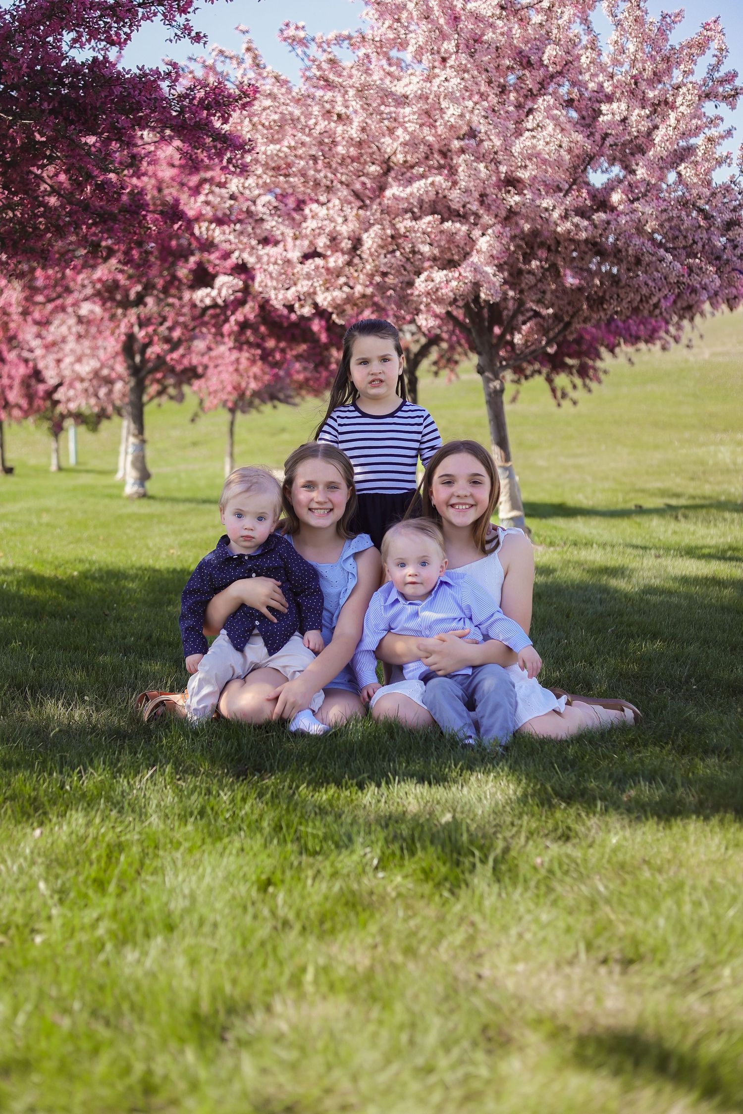 A group portrait under blooming cherry trees on a sunny spring day.