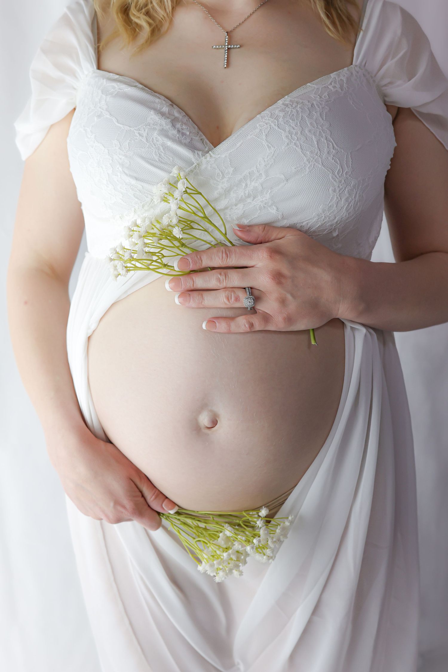 Maternity photo showing baby bump adorned with small white flowers.