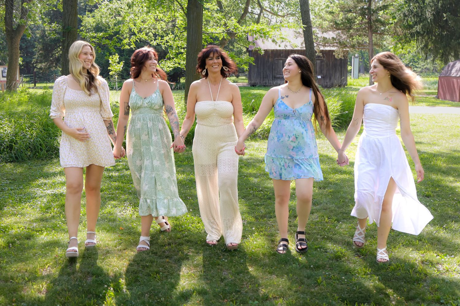 Group poses in coordinated light summer dresses and outfits in sunny outdoor setting.