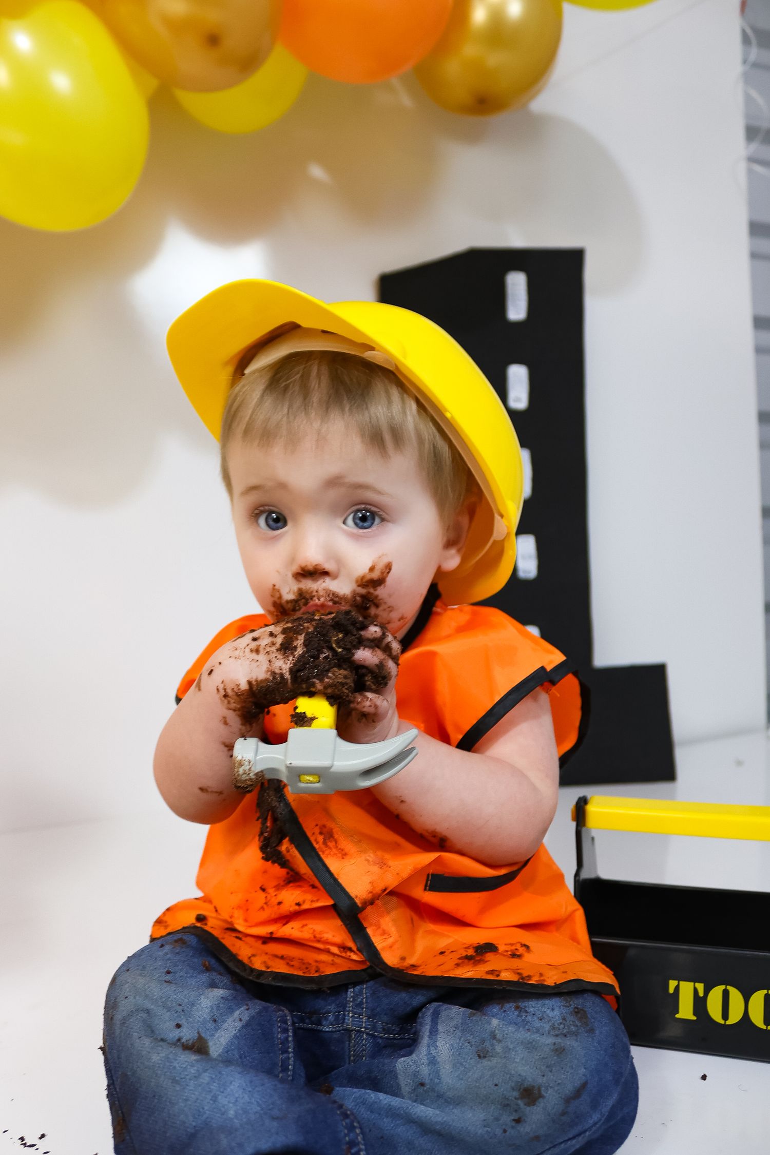 Construction themed cake smash with yellow hard hat and orange safety vest.
