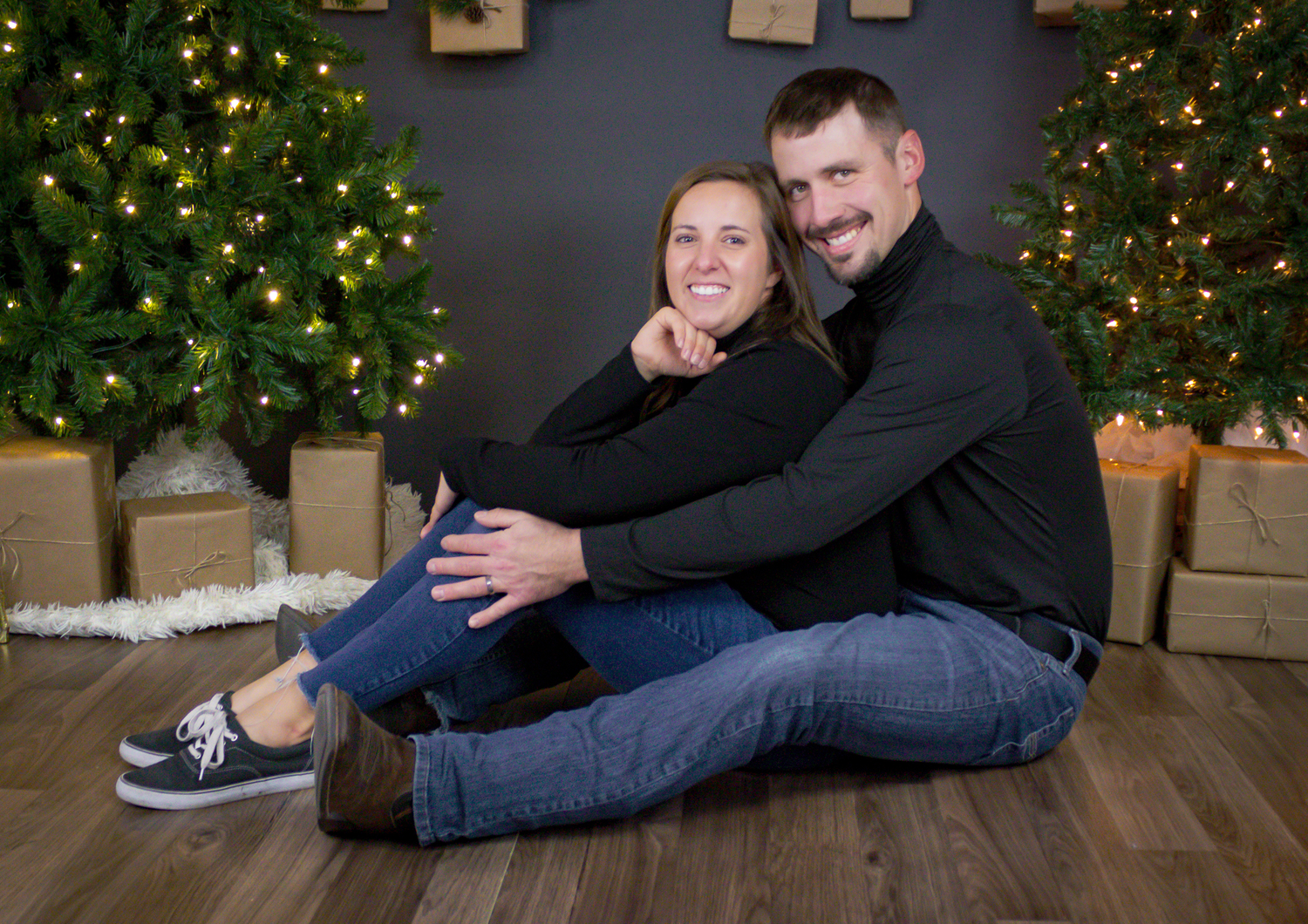 Holiday portrait session with Christmas tree and wrapped presents in background.