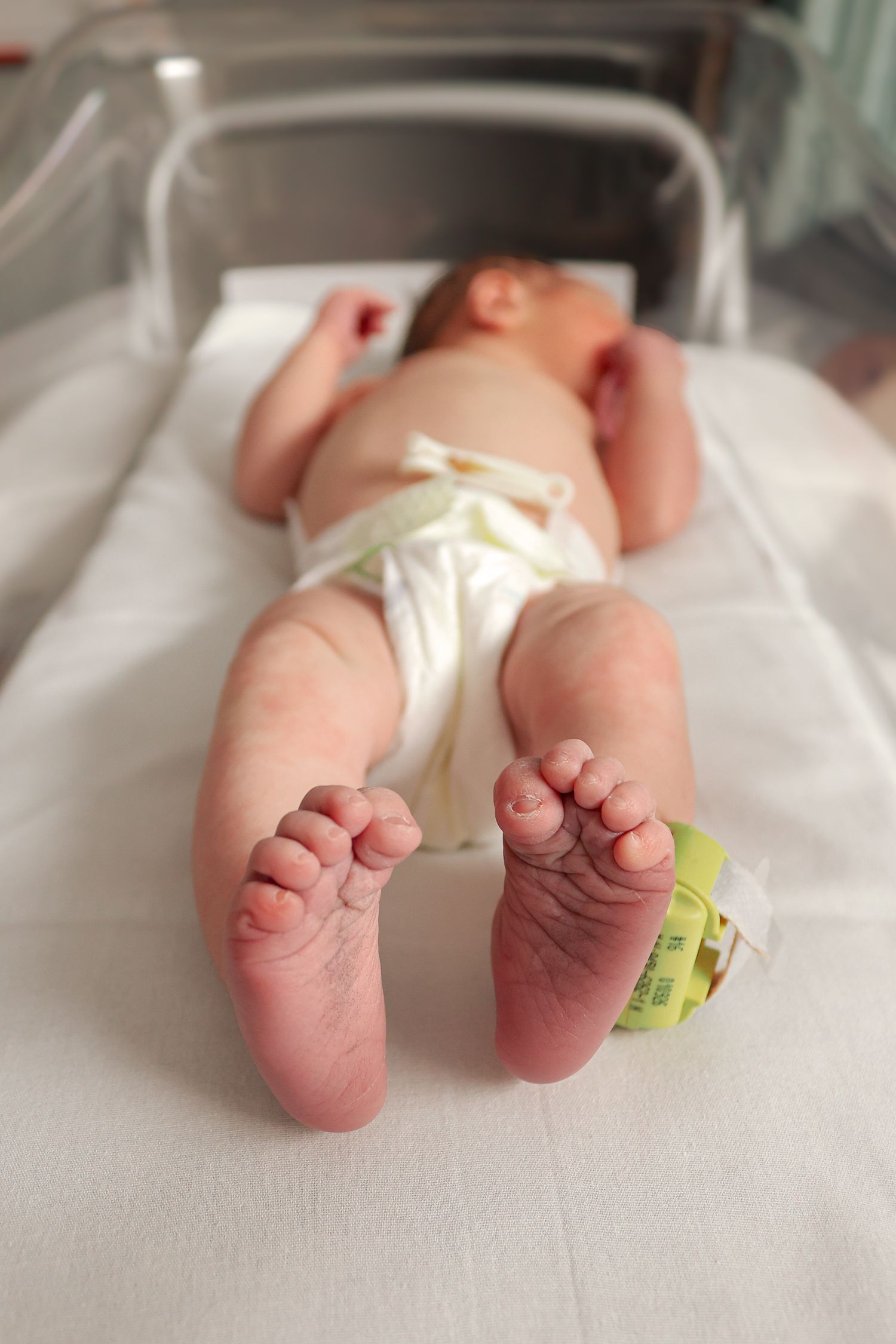 Close-up of newborn baby feet with hospital identification tag.