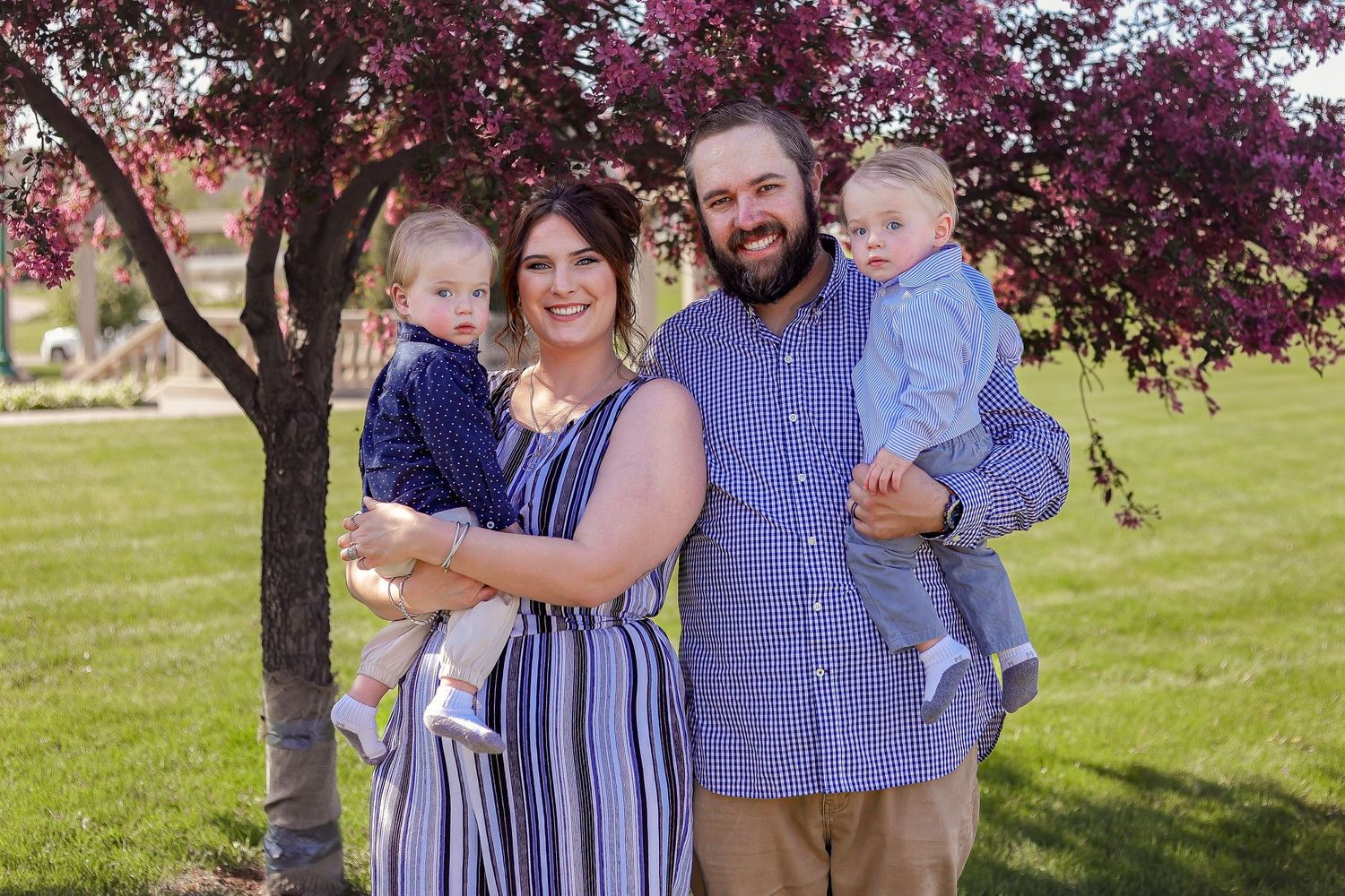 A family portrait under a blooming cherry tree with pink blossoms in the background.