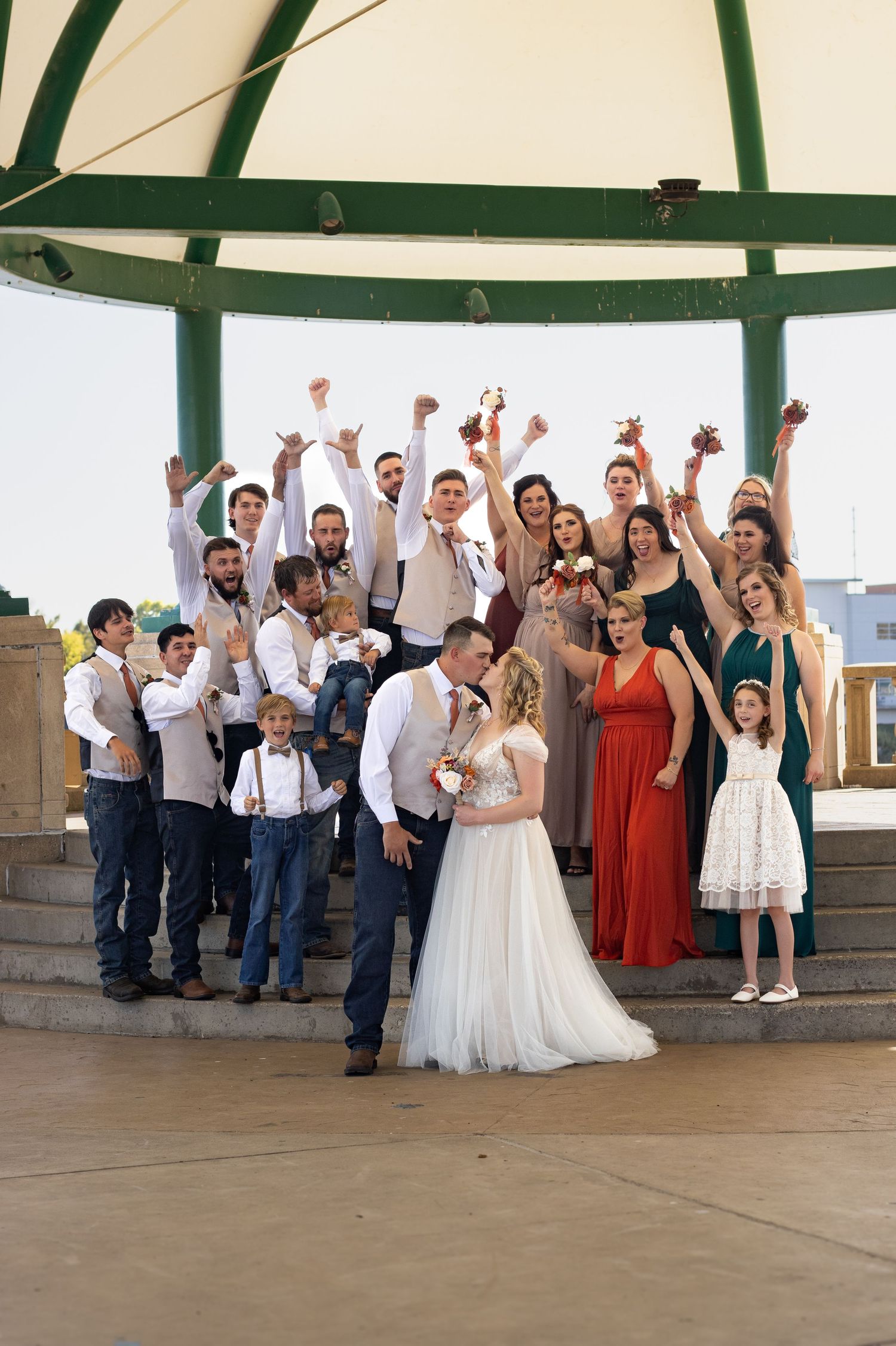 Wedding party celebration with guests in formal attire under an outdoor pavilion.