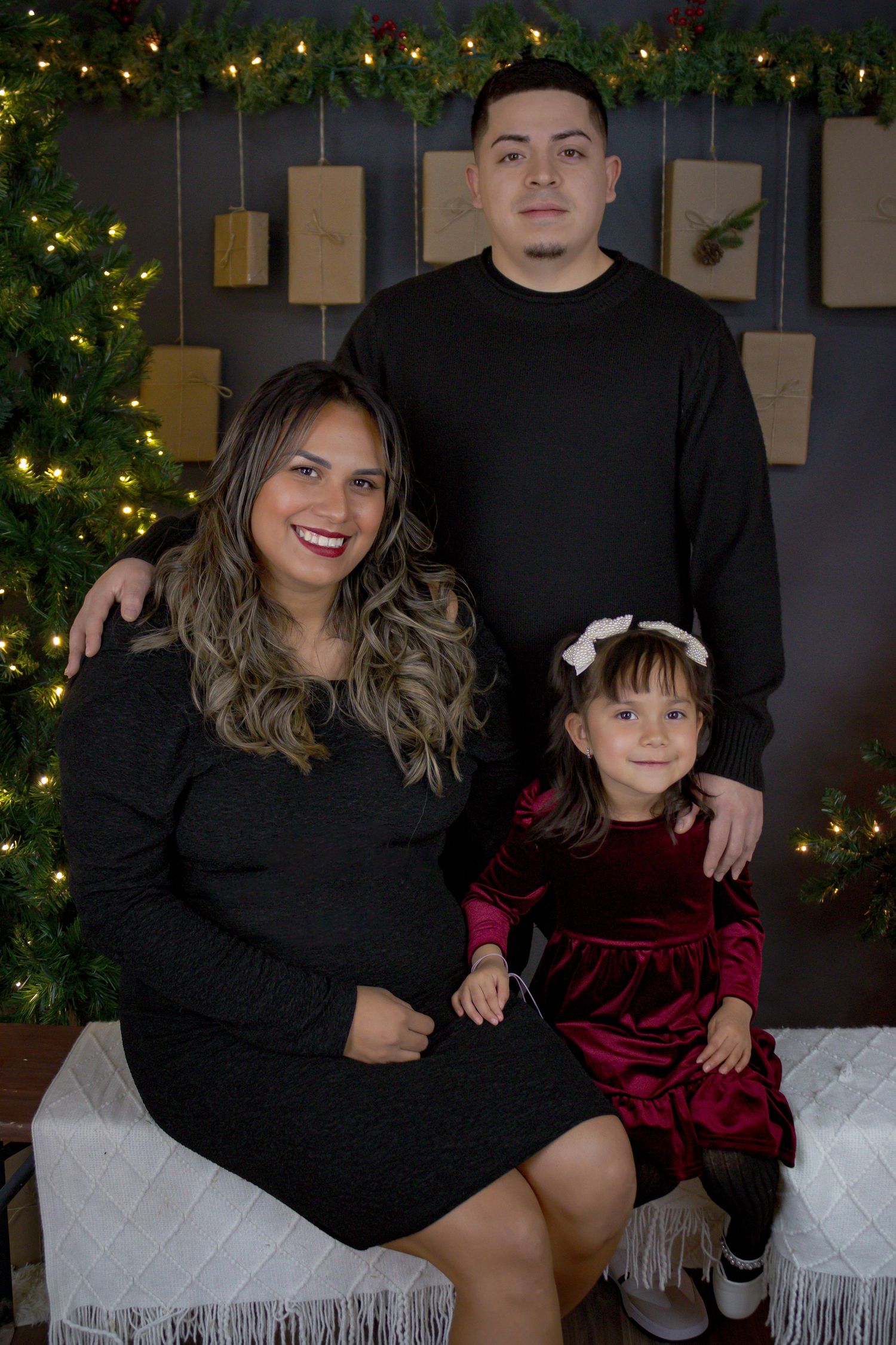 Family holiday portrait session in front of Christmas tree with coordinated black outfits.