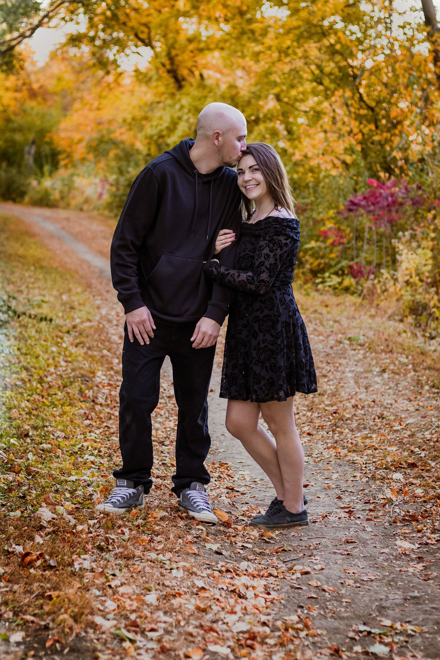 Romantic autumn engagement photos with fallen leaves on a forest path.