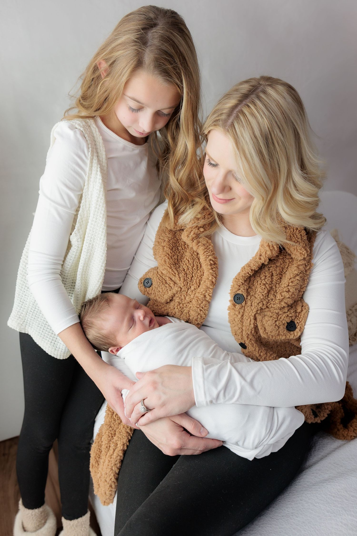 A person in white and black clothing holds a brown teddy bear while sitting in a series of intimate poses.