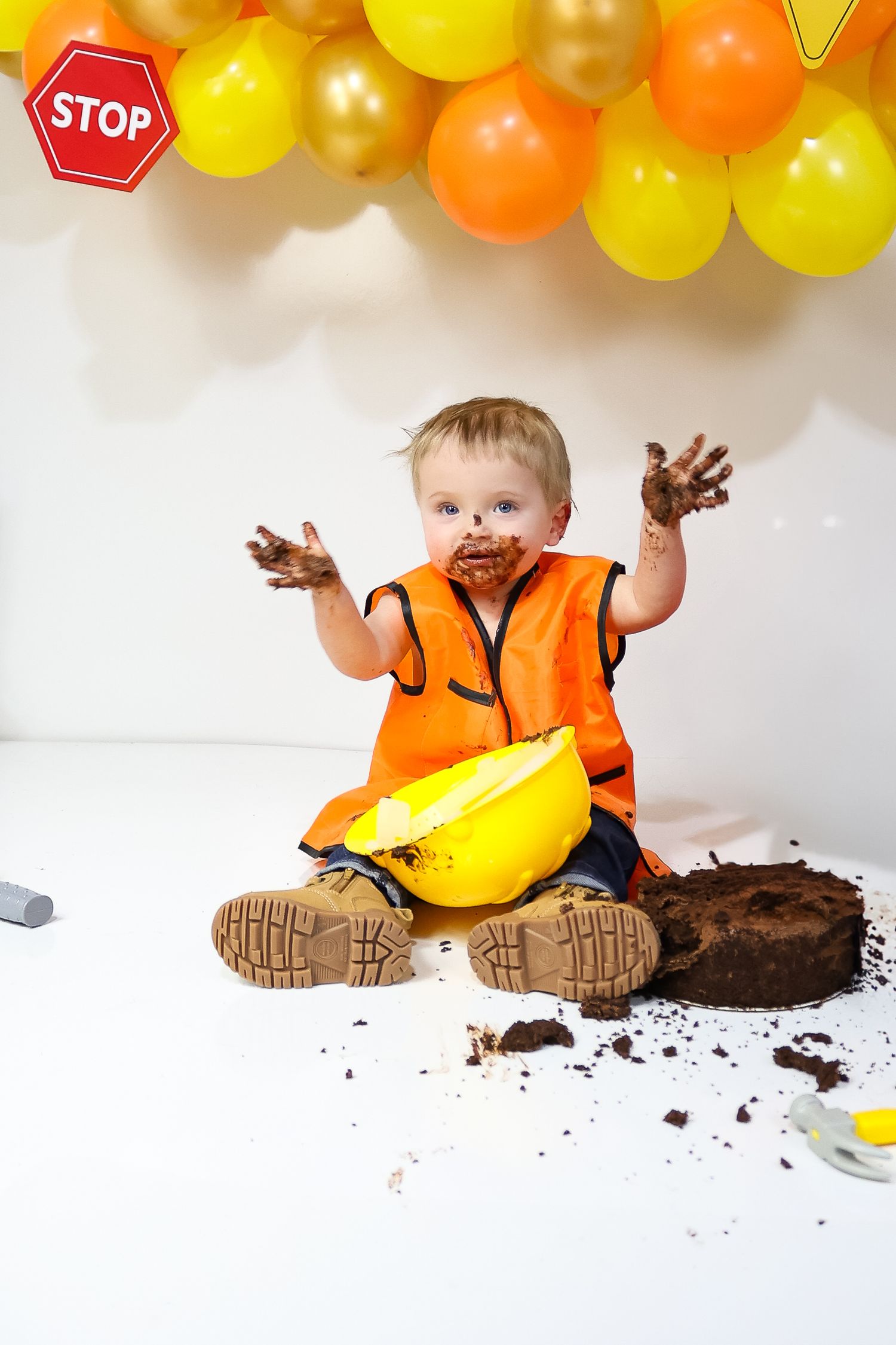 Messy cake smash scene with orange safety vest and yellow hard hat decorations.