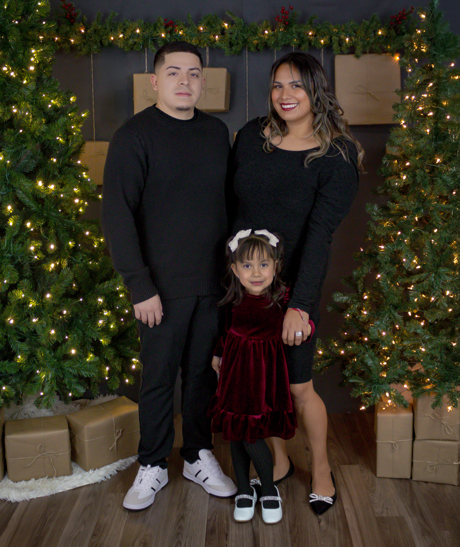 Family holiday portraits with decorated Christmas tree and wrapped presents in background.