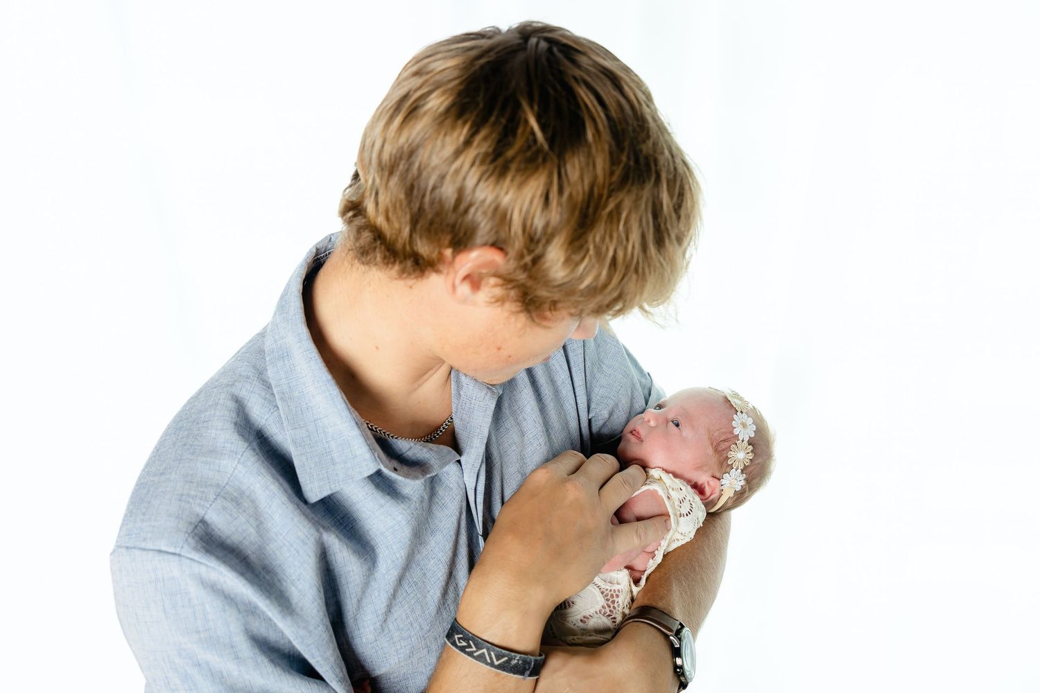 A tender moment showing a baby being cradled and comforted in a light blue shirt.