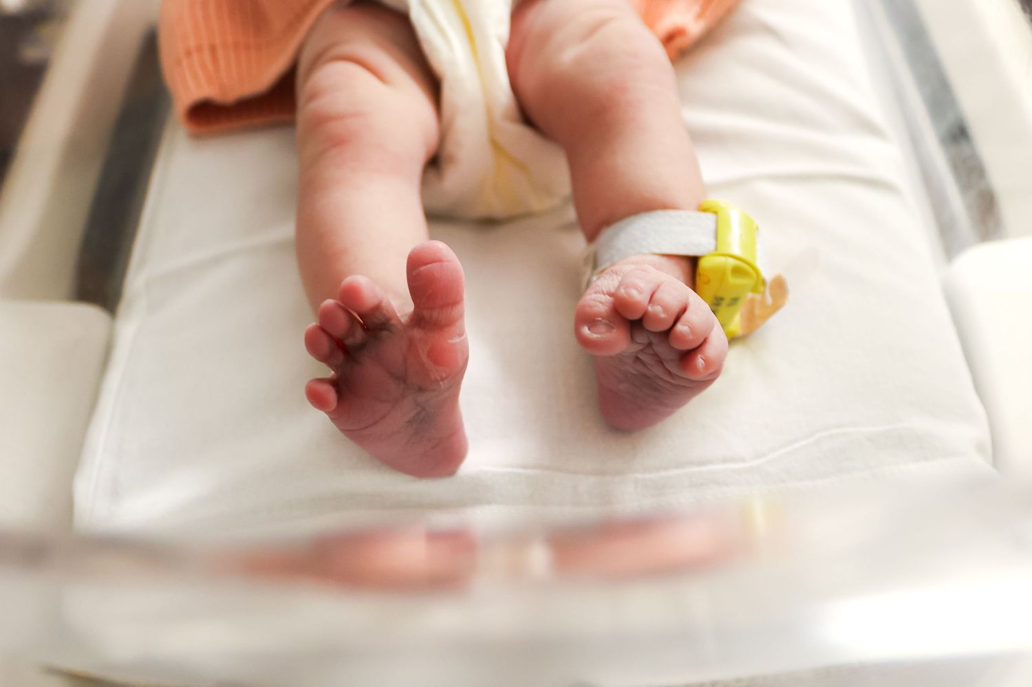 Close-up of tiny newborn feet resting on white hospital bedding.
