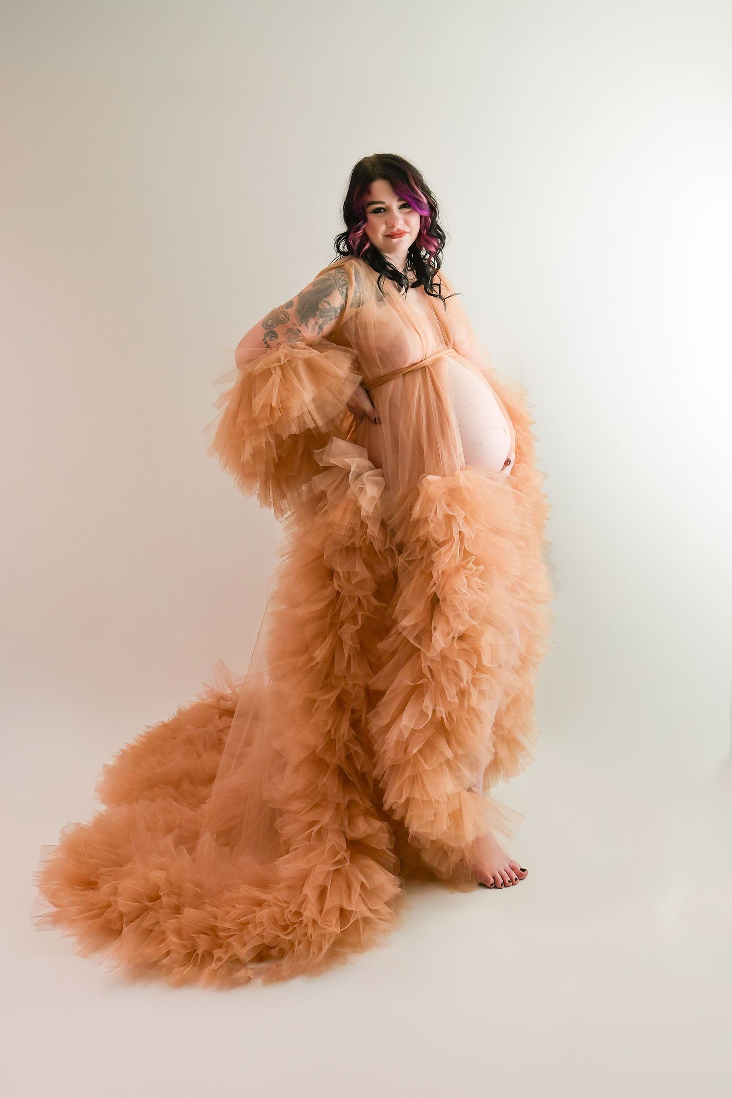 A person in a flowing peach-colored tulle gown poses gracefully against a light backdrop in a photo series.