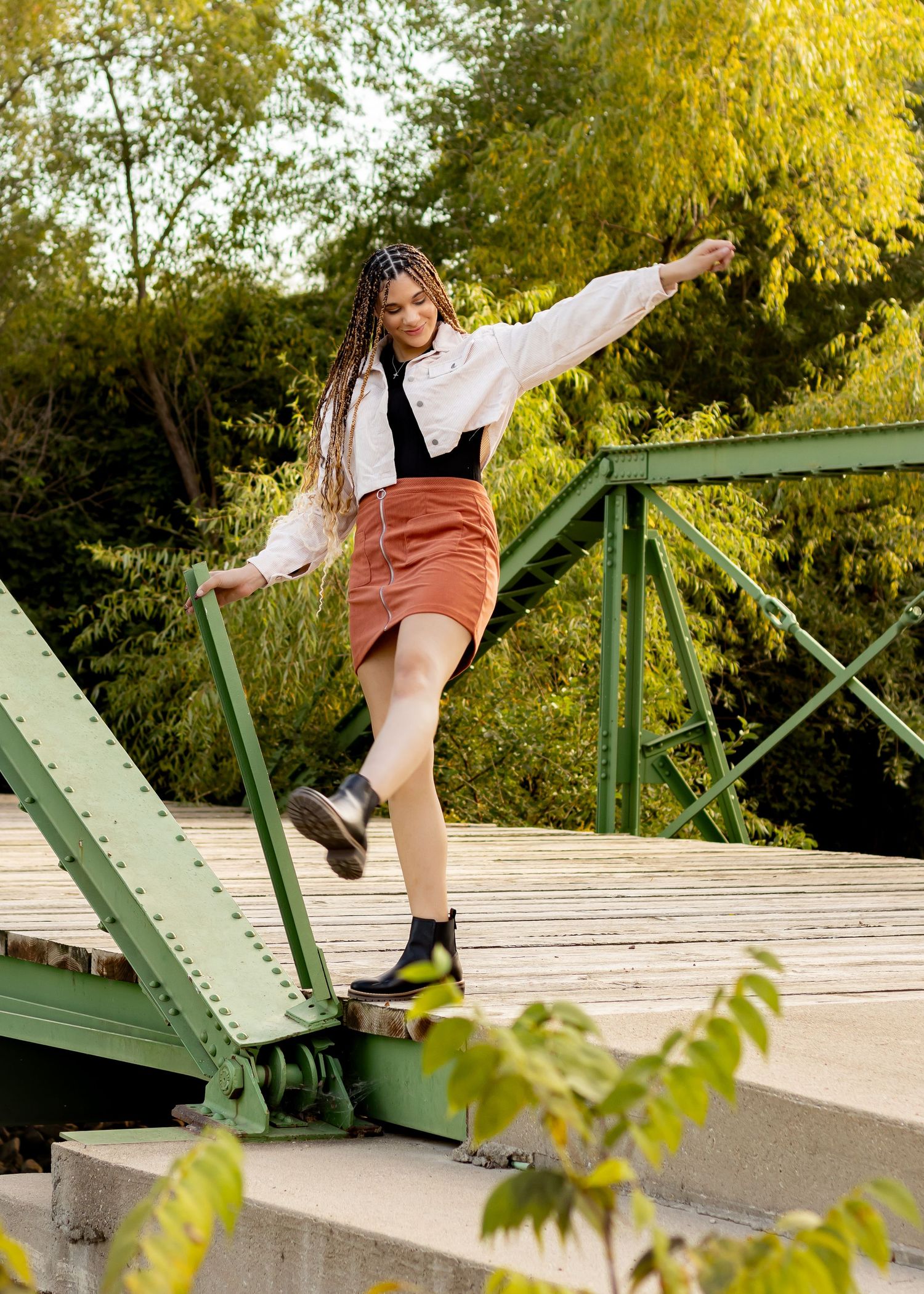 Dynamic dance poses on a wooden bridge with autumn foliage in background.