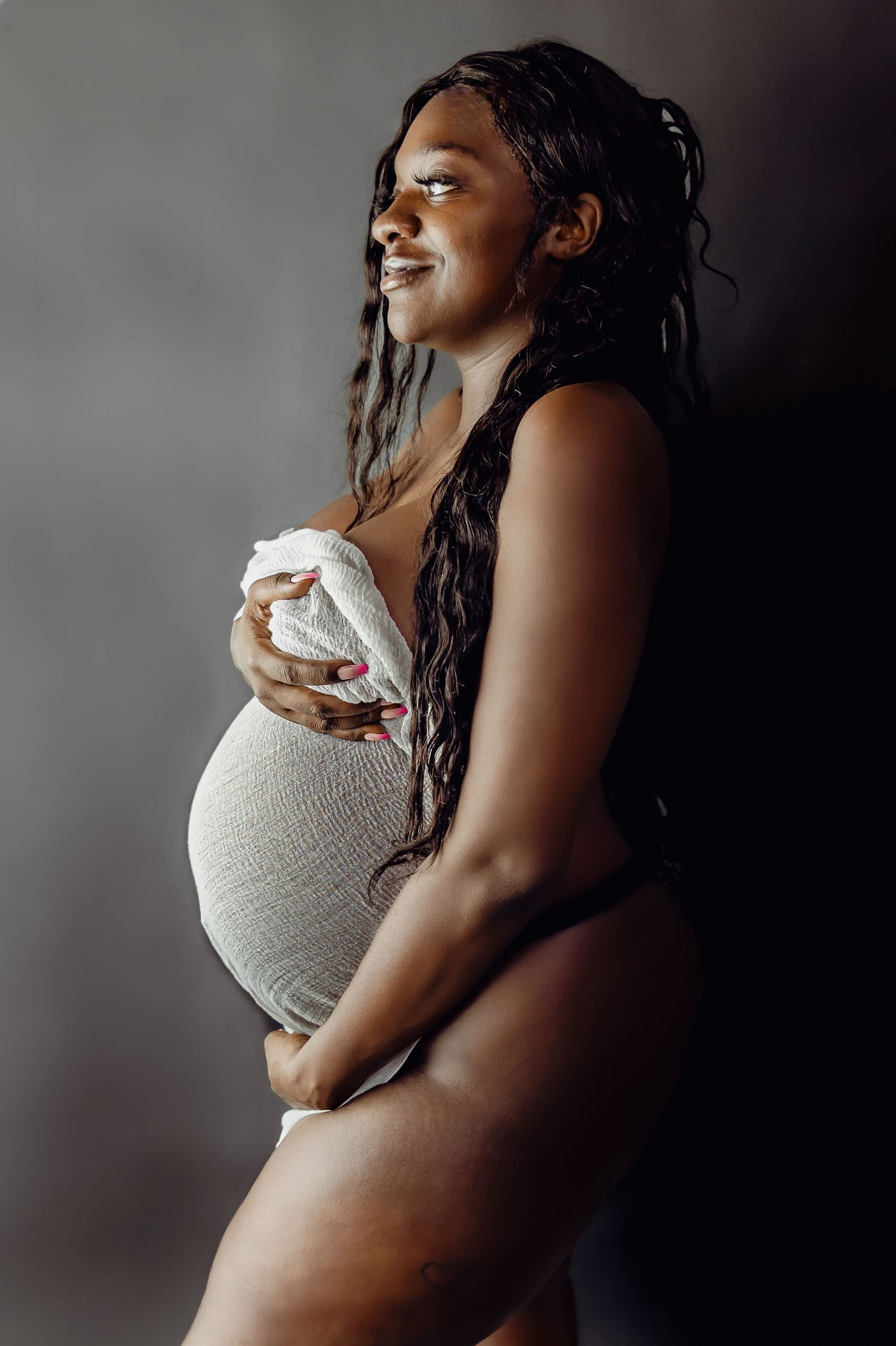 Intimate pregnancy portrait with soft lighting and grey fabric.