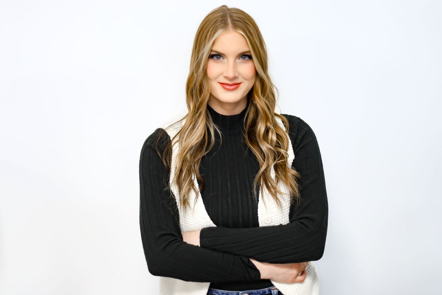 Stylish model in black turtleneck sweater posing against white background for fashion photoshoot.