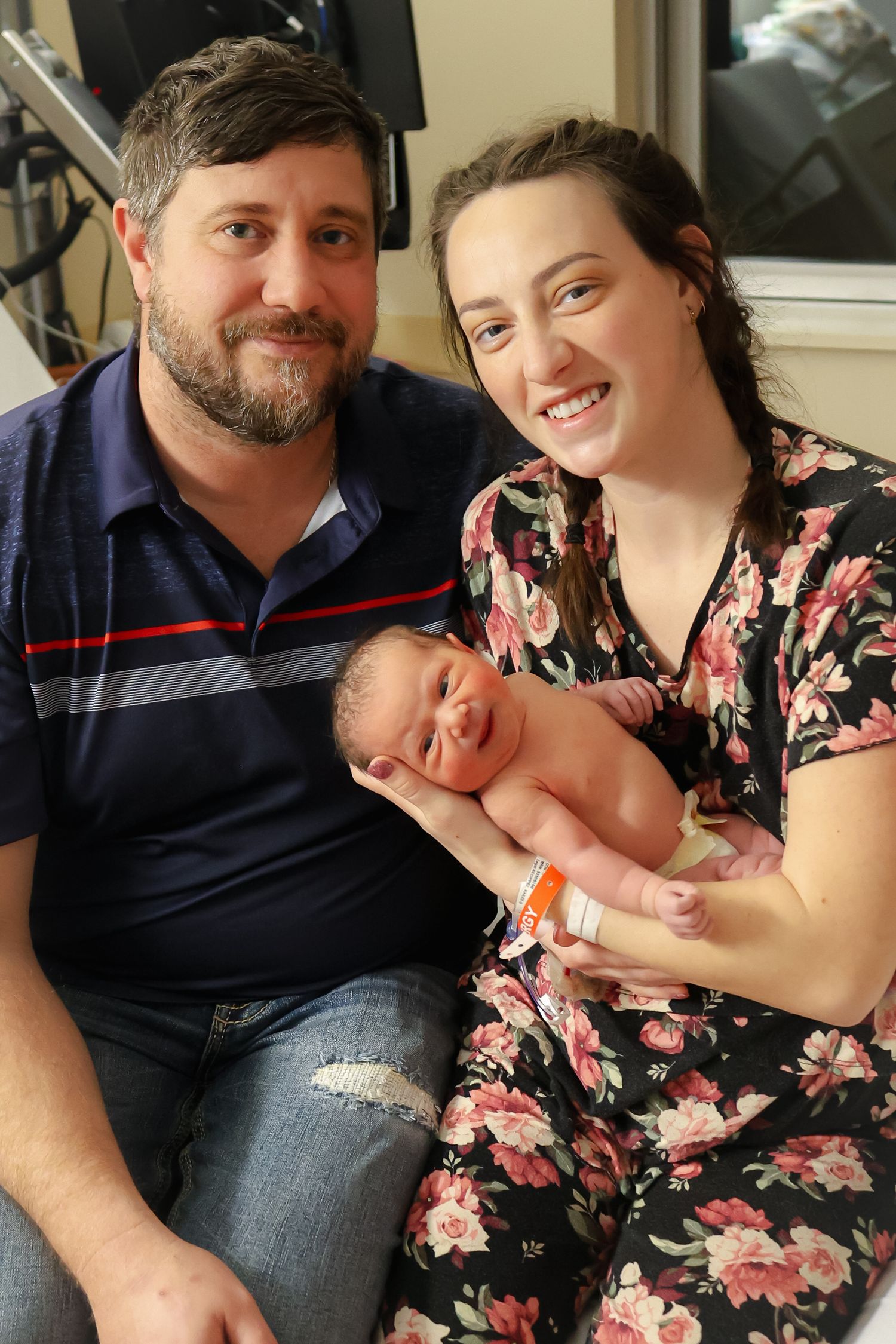 New parents sharing a tender moment with their newborn in the hospital room.