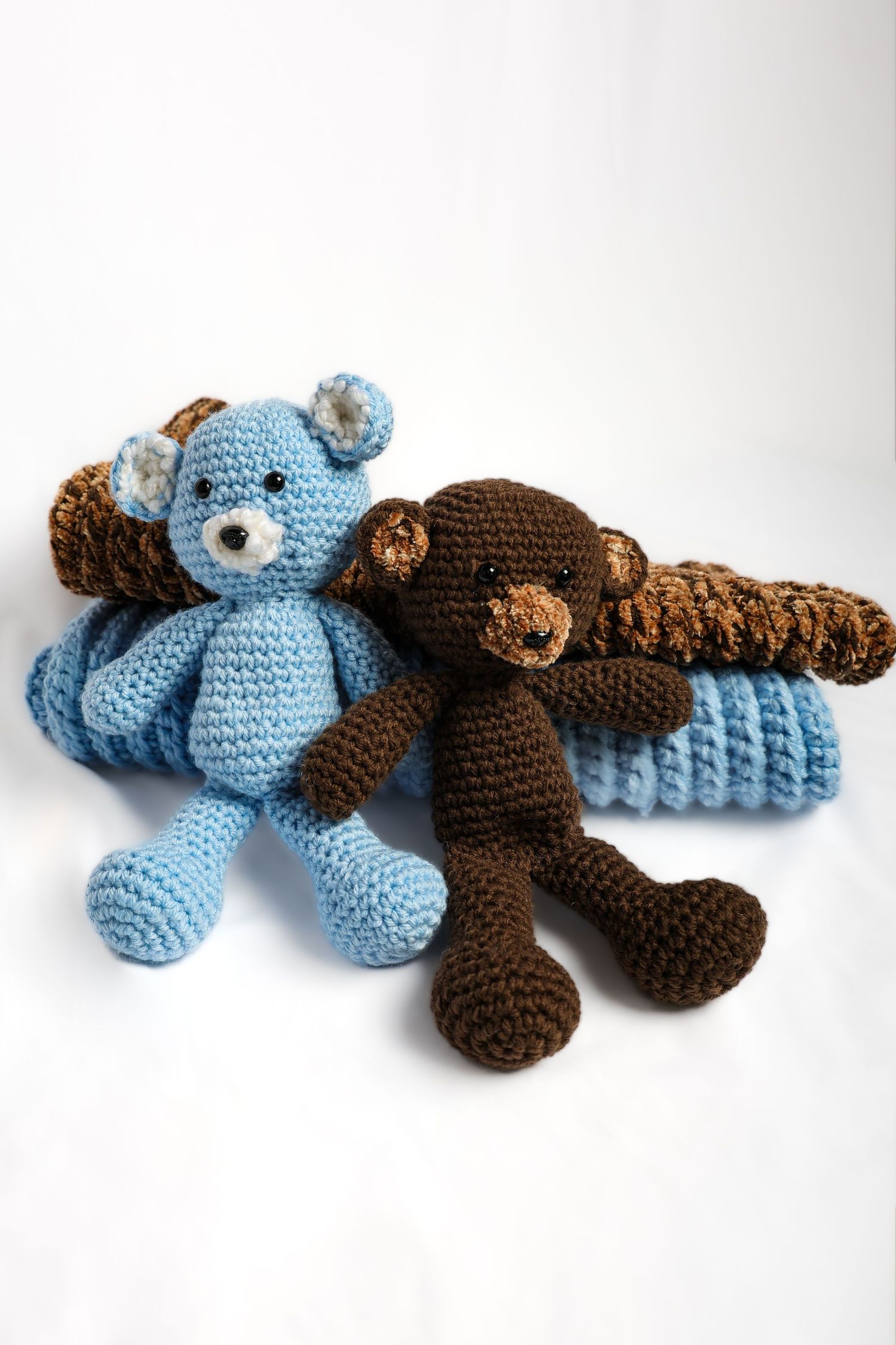 Handcrafted crochet teddy bears in blue and brown laying together.