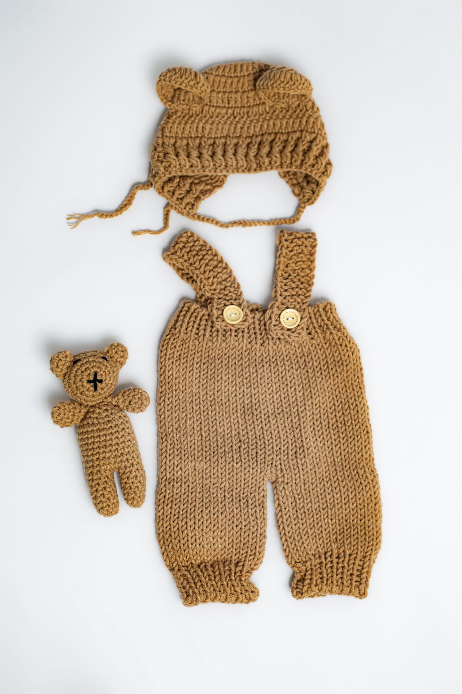 Knitted brown baby overalls and matching teddy bear accessory set.