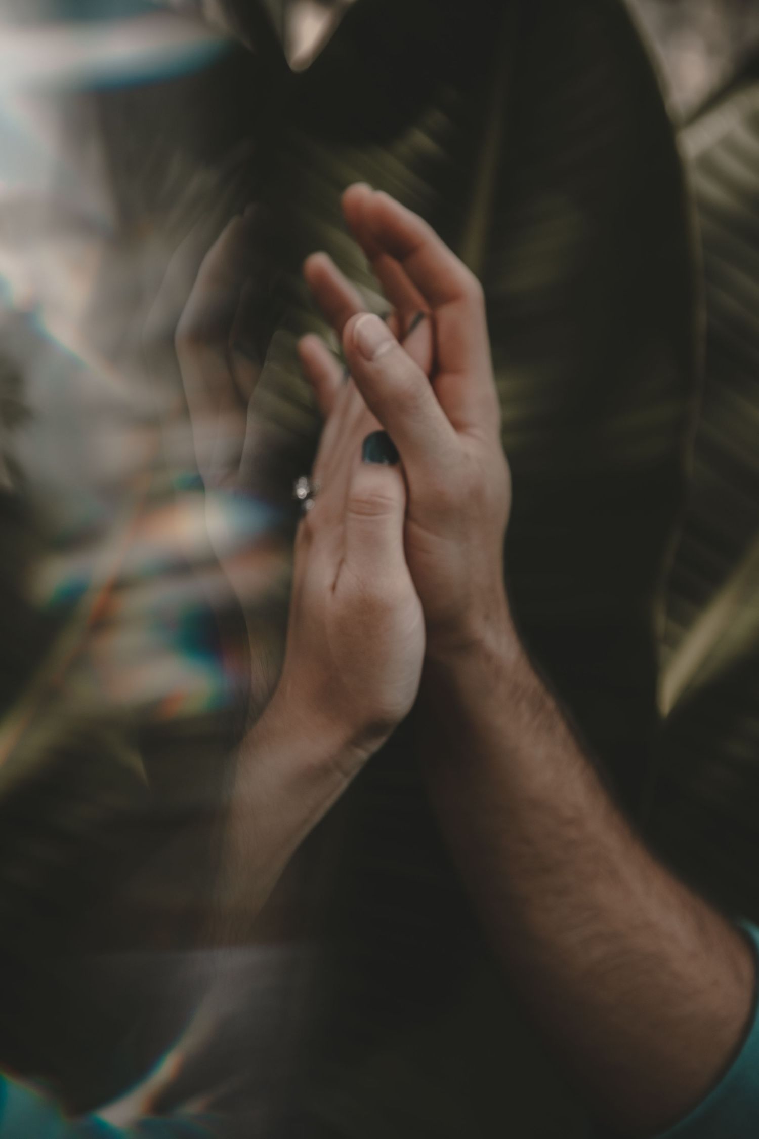 Two hands come together in a tender moment captured through dreamy, filtered photography.