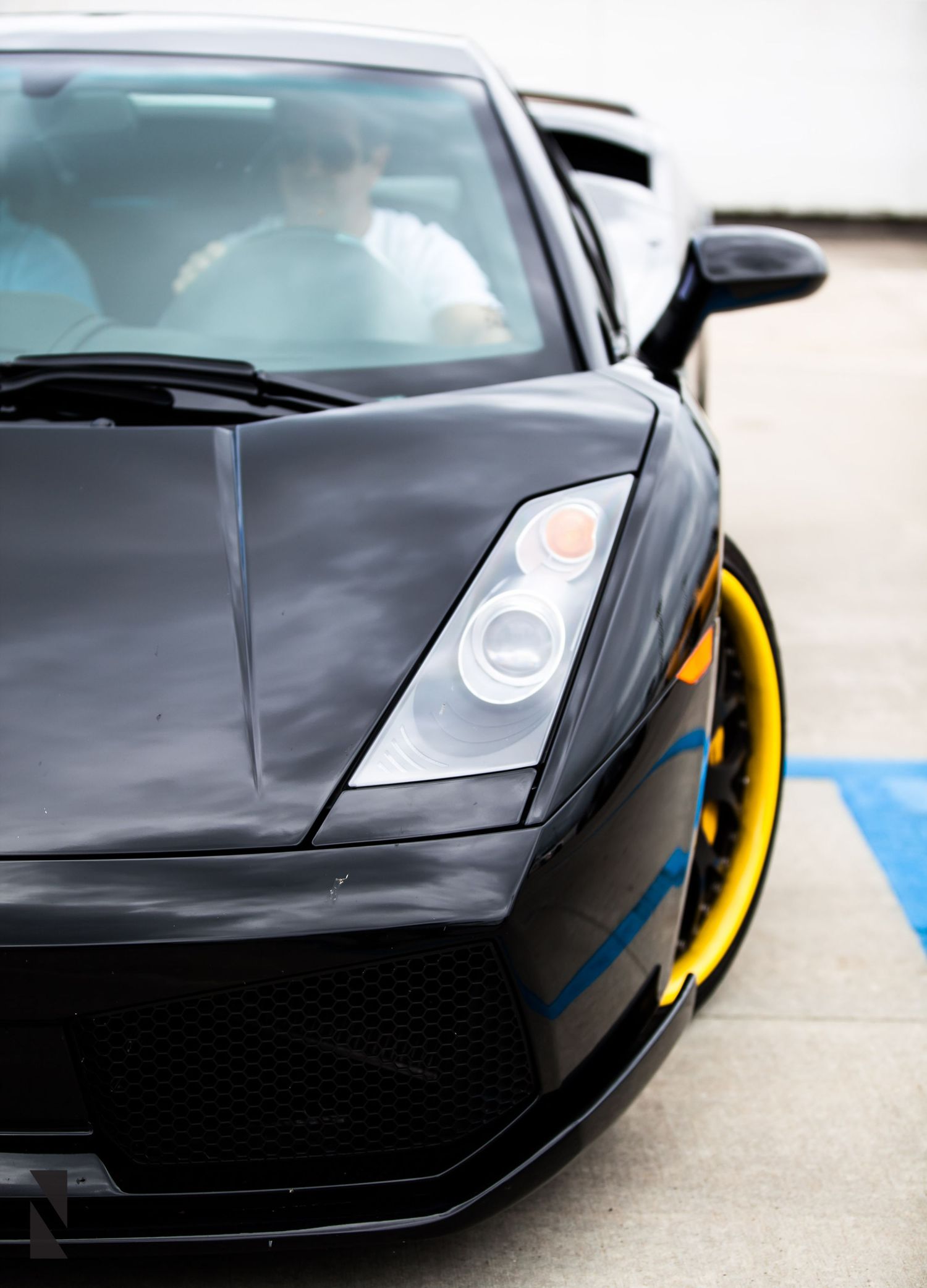 Close-up view of a black Lamborghini supercar's front end showing sleek headlights and aggressive styling.