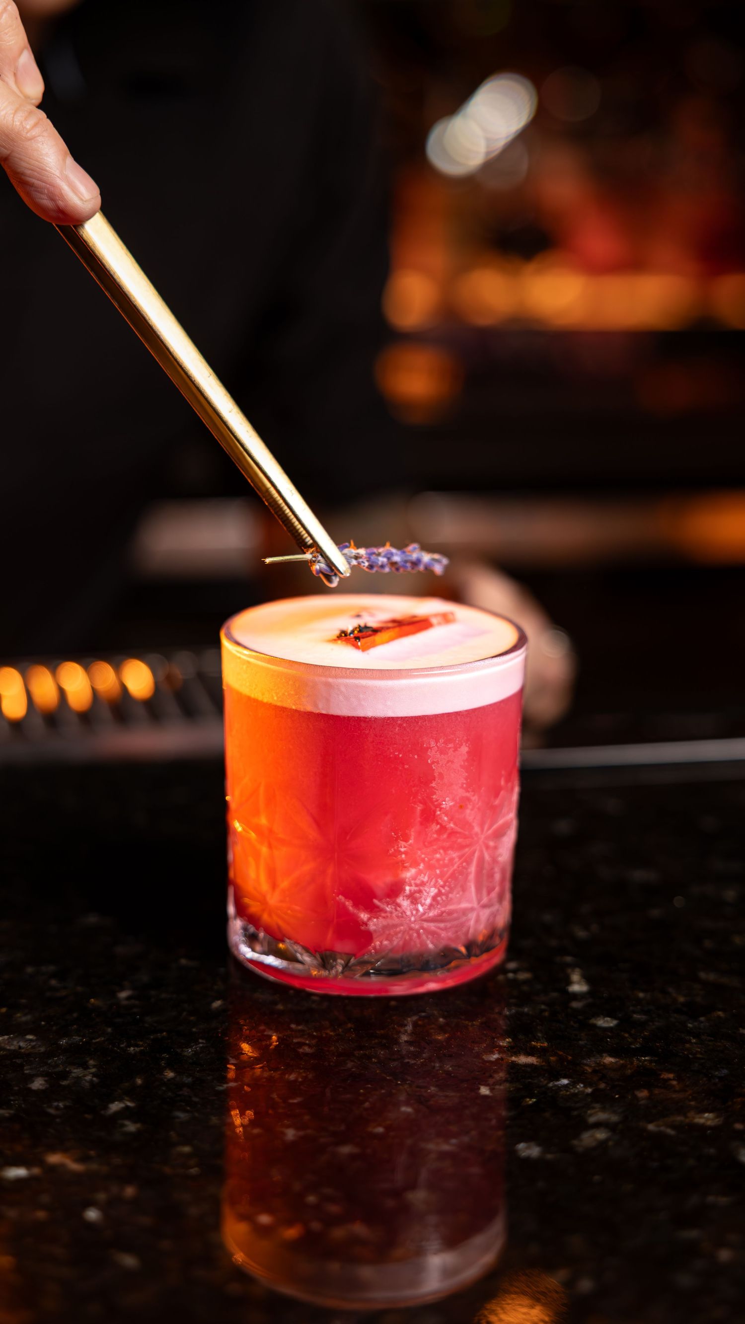 A red craft cocktail with frost-covered glass gets garnished with a gold straw across multiple sequential photos.