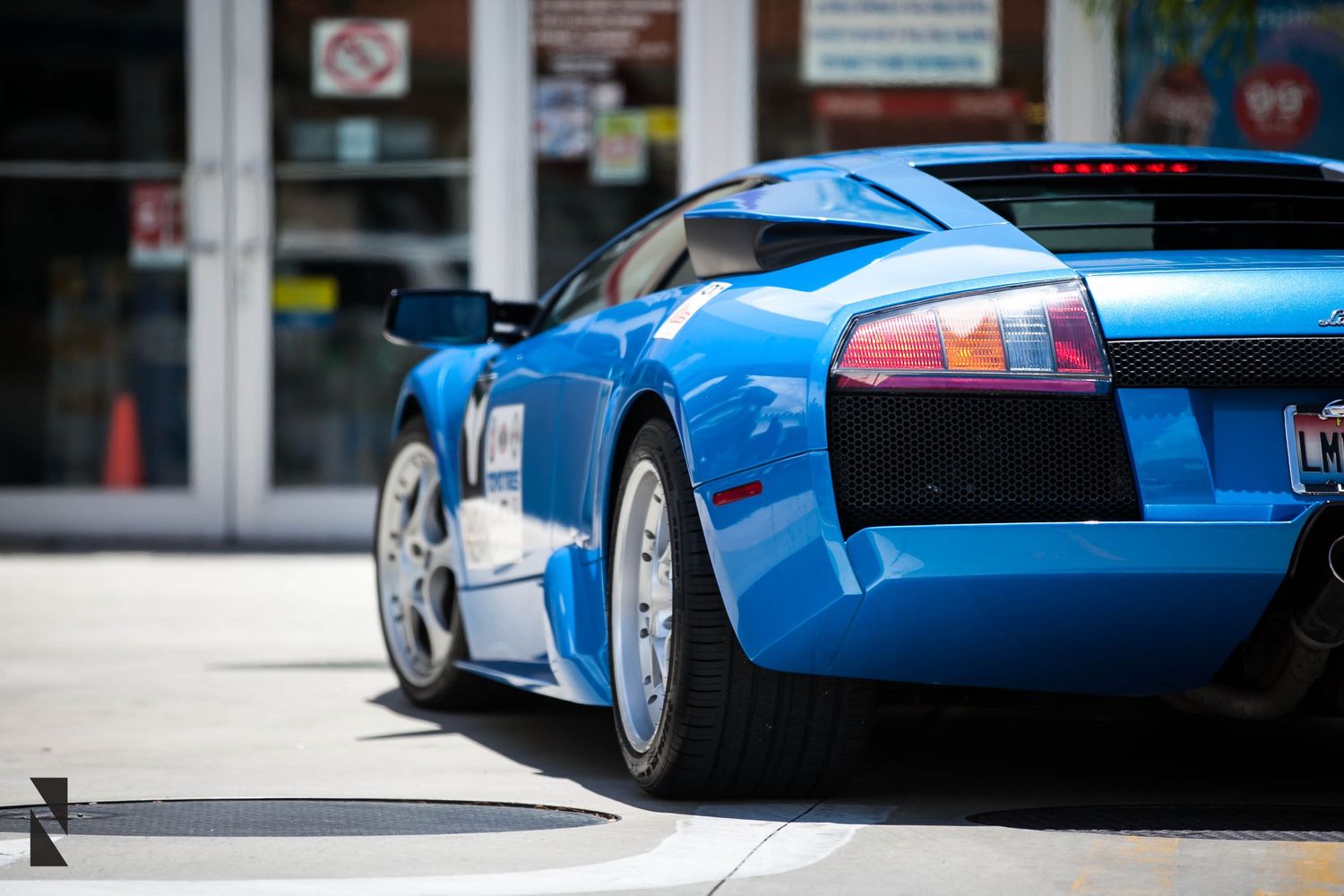 Rear quarter view of a bright blue Lamborghini Murcielago showcasing its distinctive taillights and wheels.