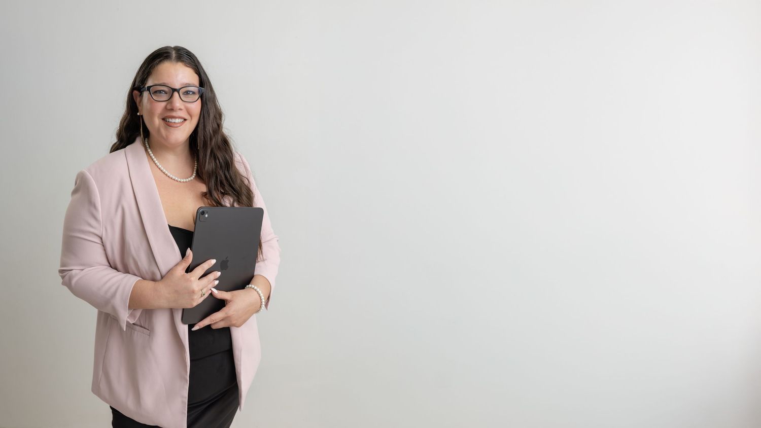 A person in a pink blazer and glasses reviews content on a handheld device while facing different angles.