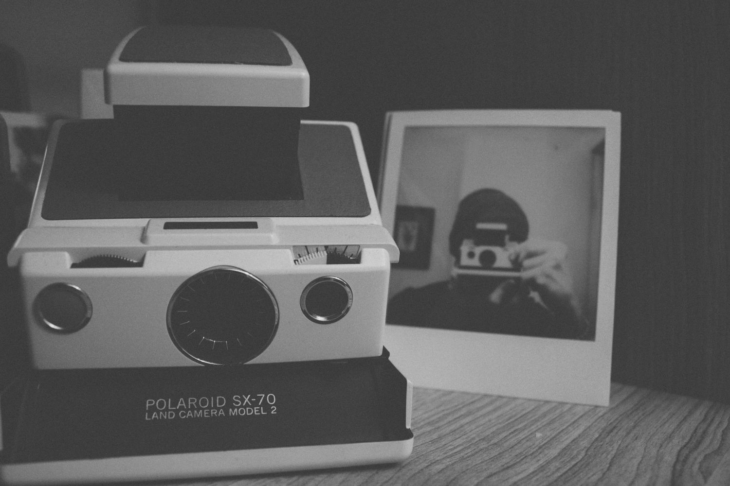 Black and white still life of retro Polaroid camera with photo print.